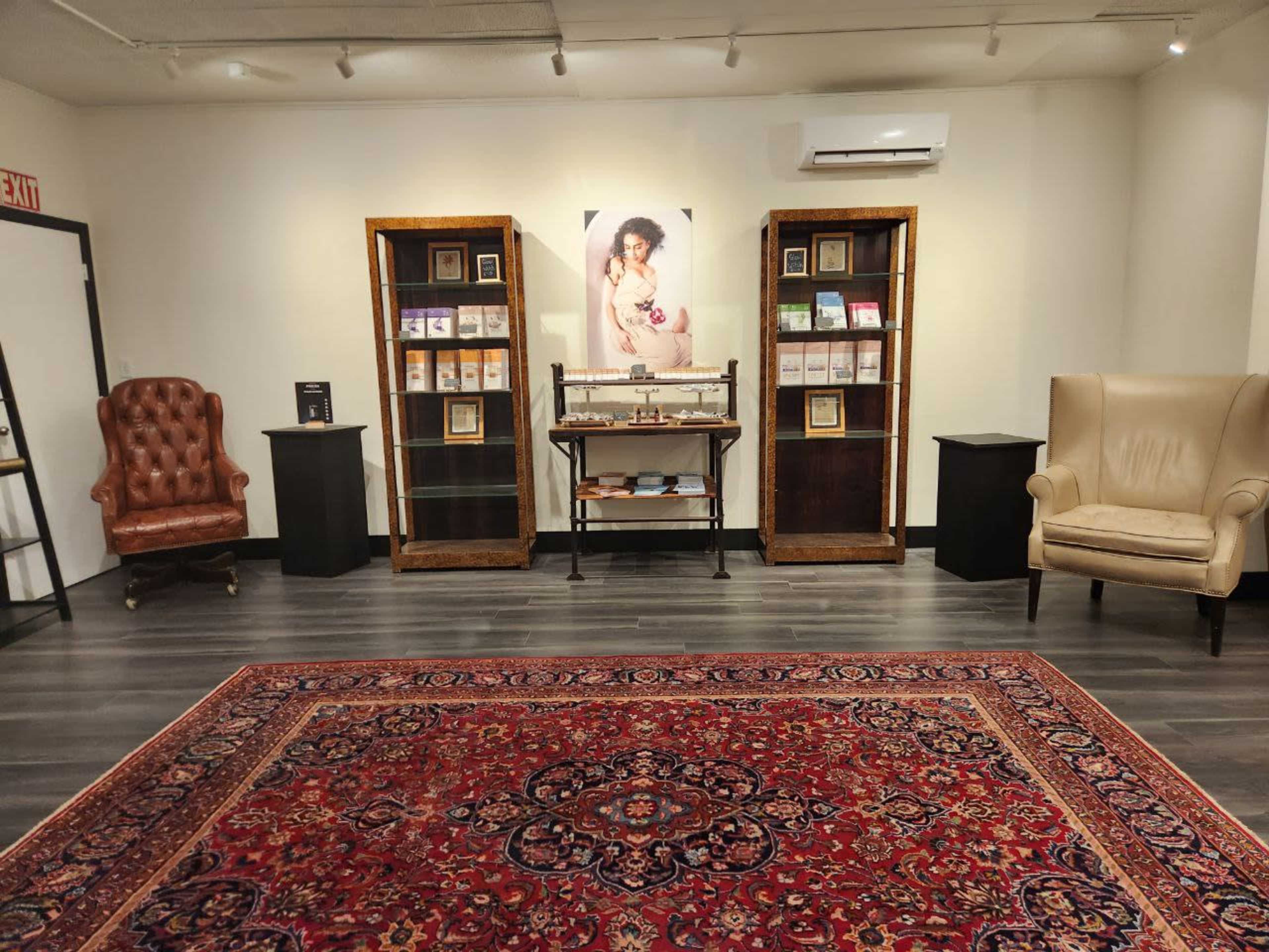 A well-arranged interior space featuring two armchairs, display cases with books, and a prominent portrait on the wall.