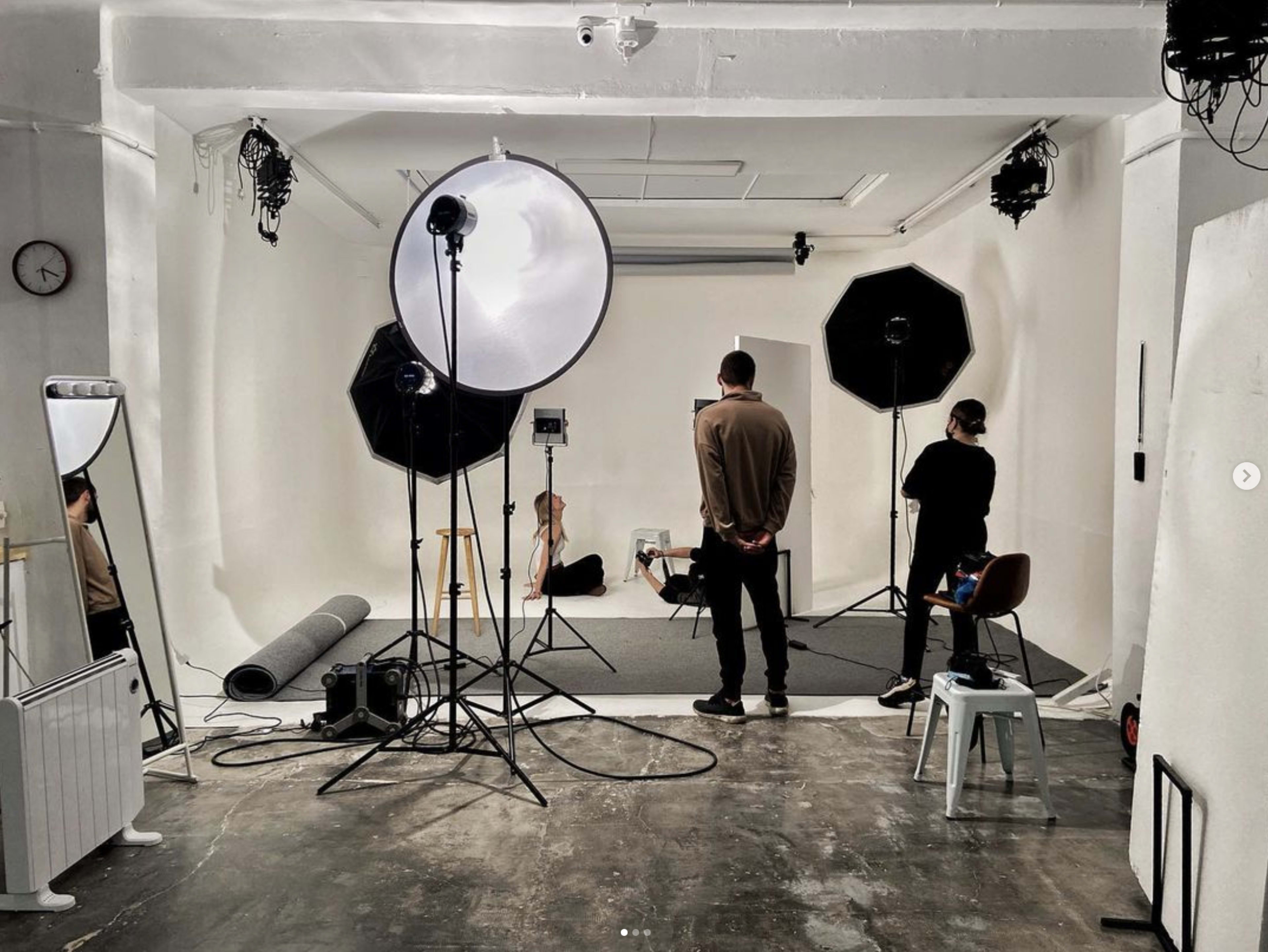 A photography studio is set up with multiple lighting equipment, backdrops, and props arranged for a shoot.