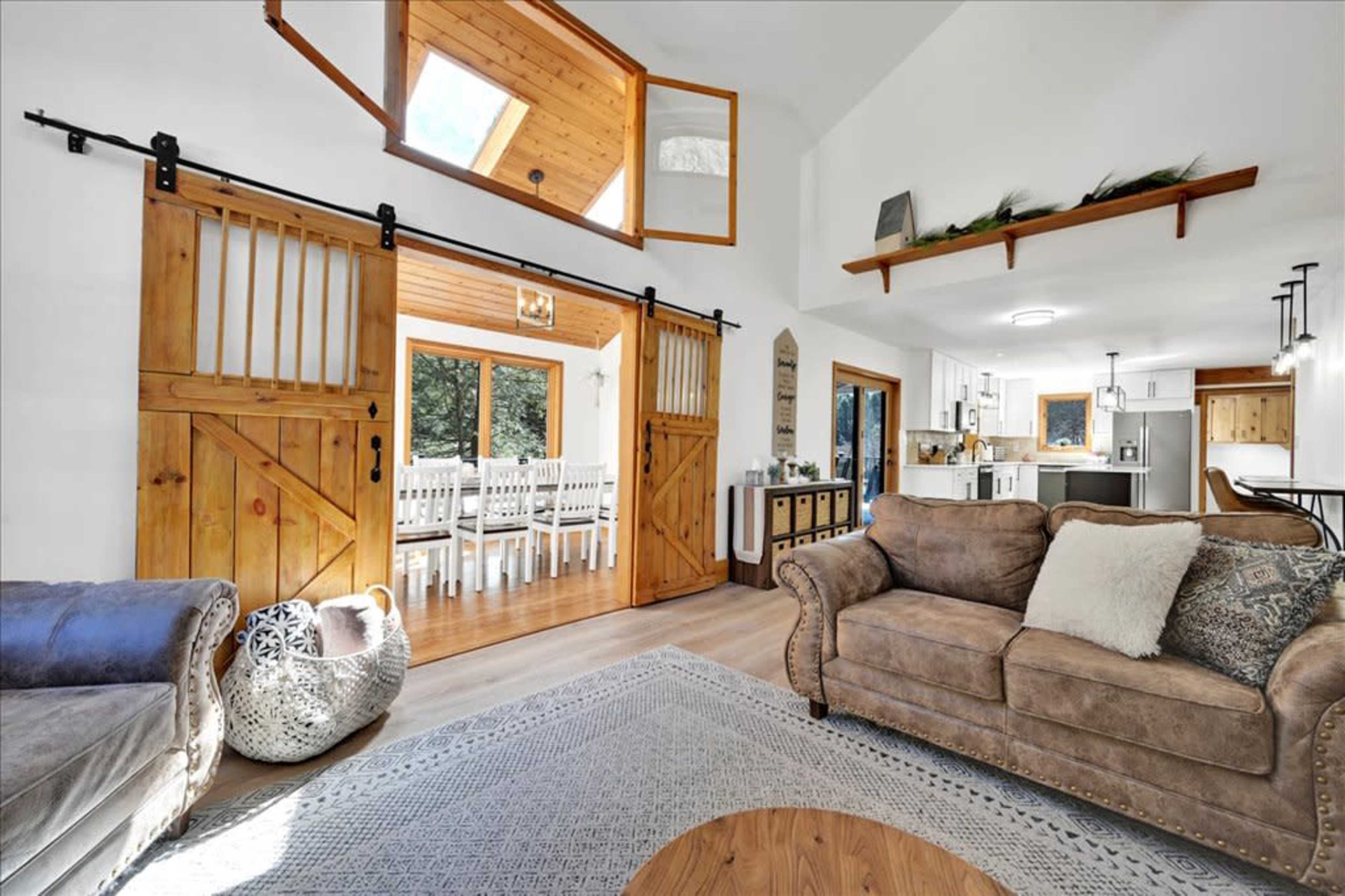 A cozy living area featuring a brown sofa, decorative pillows, and a wooden coffee table, with a sliding barn door leading to a dining area.