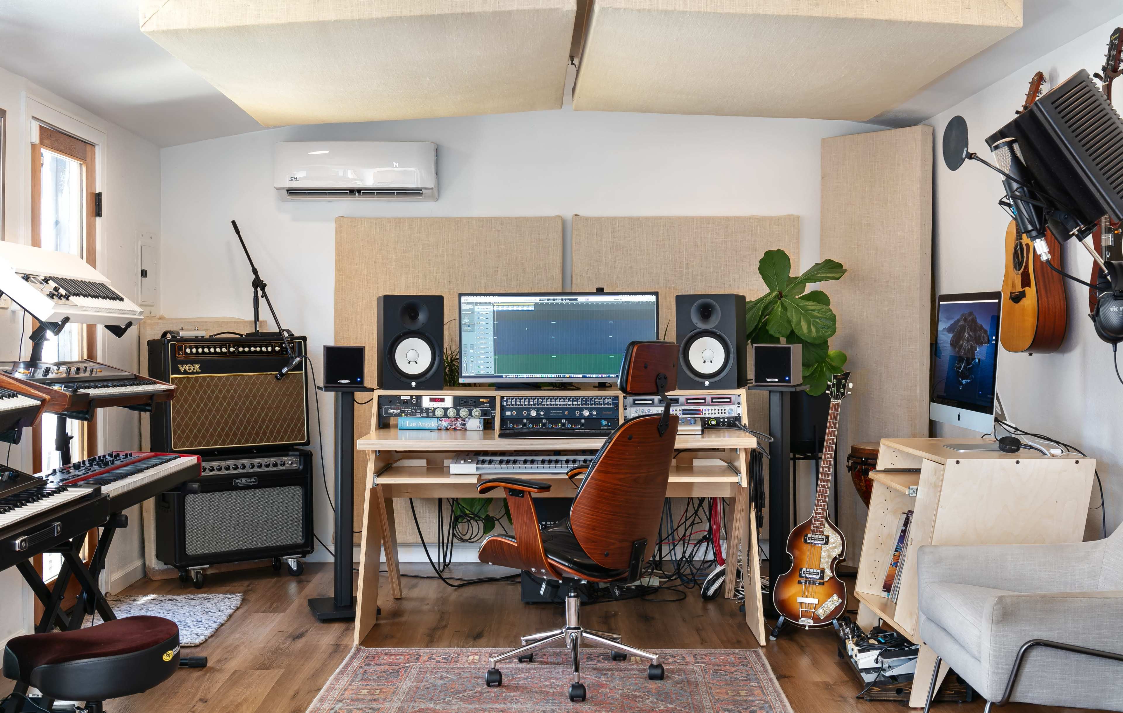 A music studio with various instruments, a computer workstation, and sound equipment arranged around a central chair.