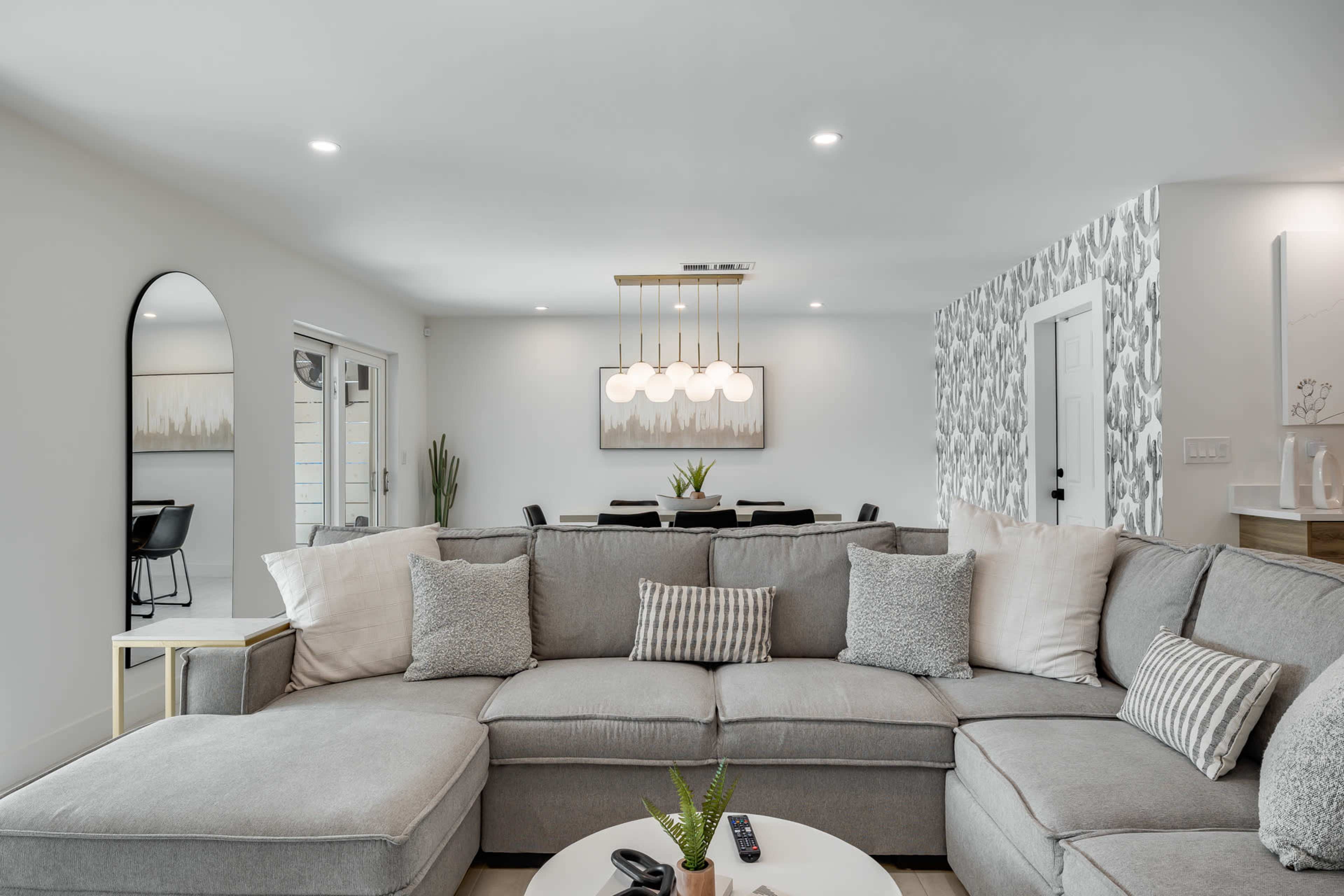 A modern living room featuring a large gray sectional sofa with decorative pillows, a coffee table, and framed artwork on the walls.
