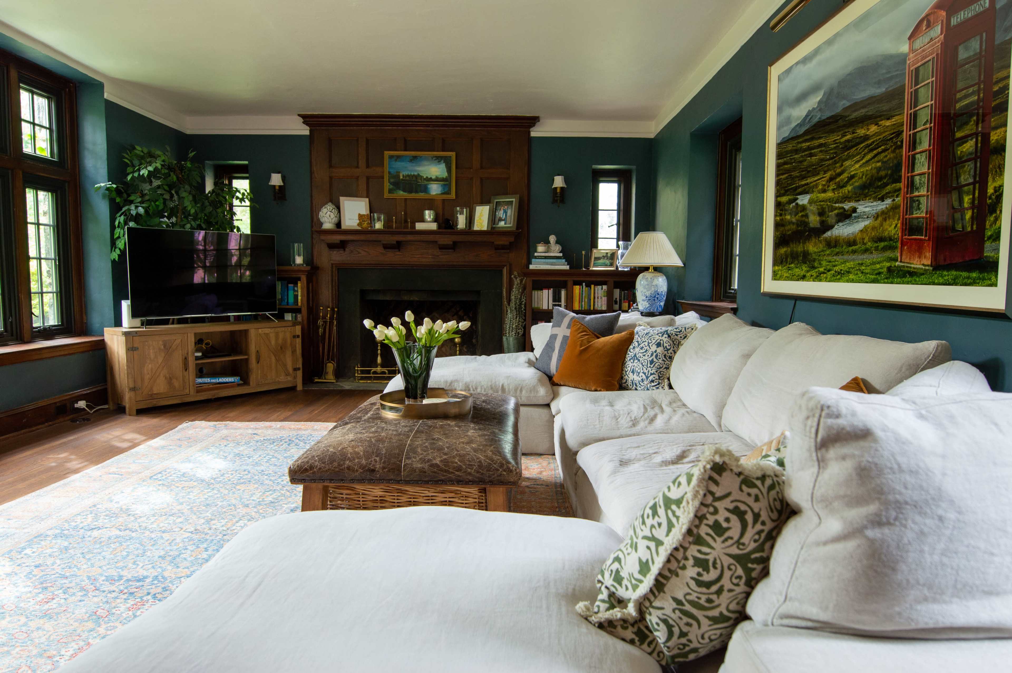 The living room features a large sectional couch, a coffee table, a television, and a fireplace, with large windows allowing natural light to fill the space.