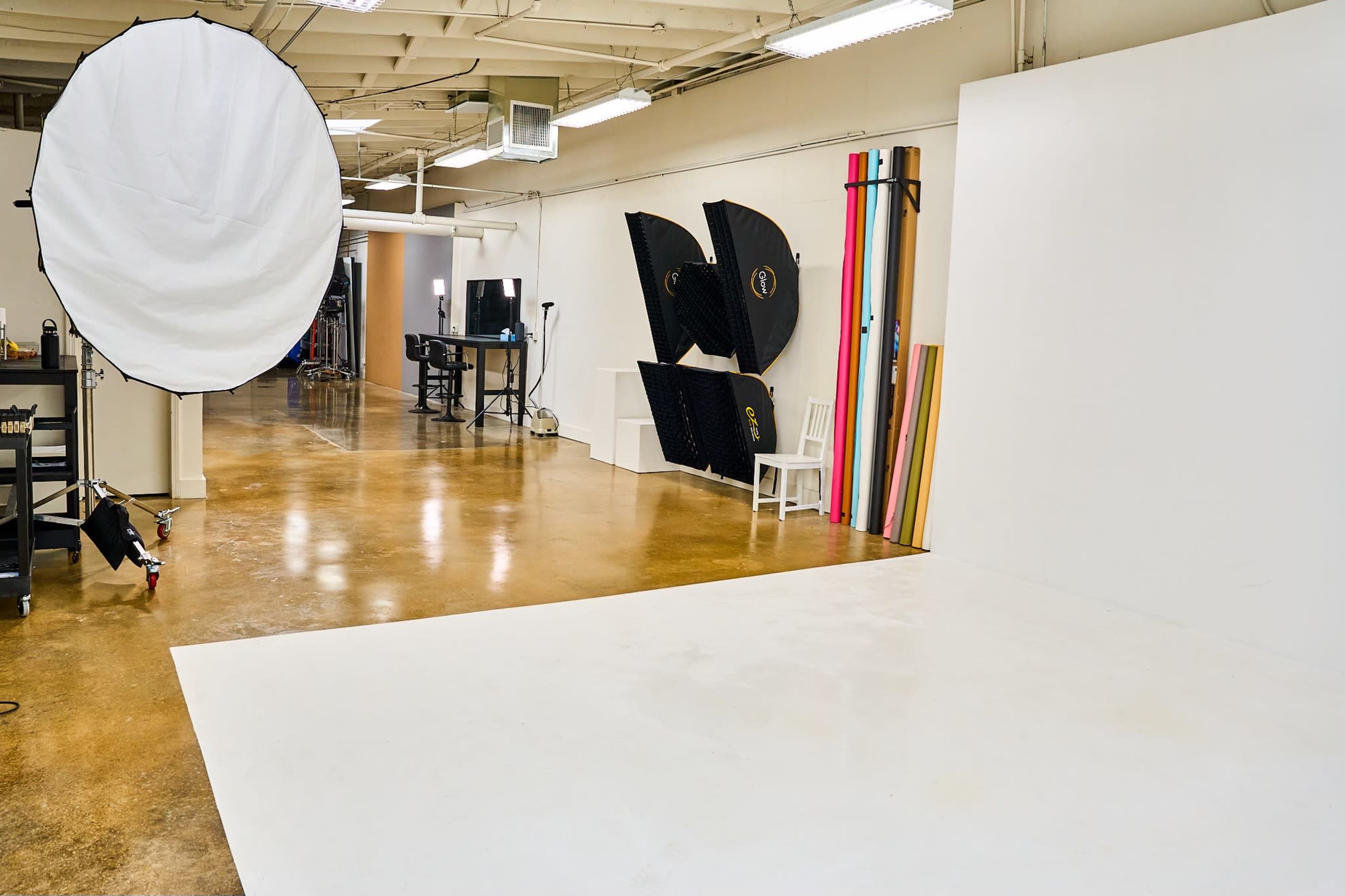 A photography studio with a backdrop, lighting equipment, and a clean, empty floor.