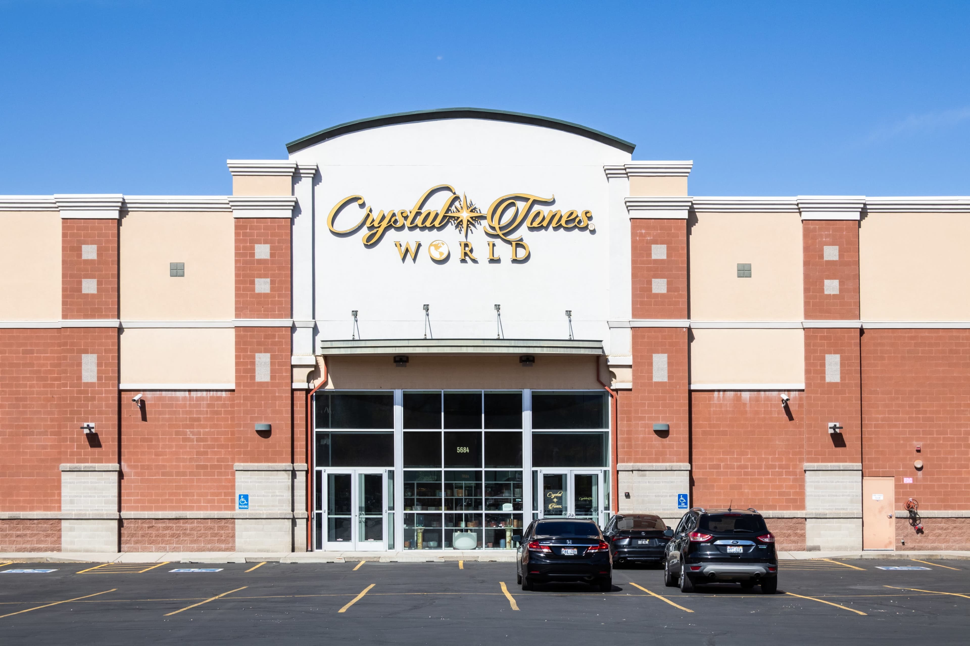 The image shows the exterior of a commercial building featuring the sign "Crystal Tones World" above the entrance, with several parked cars in front.