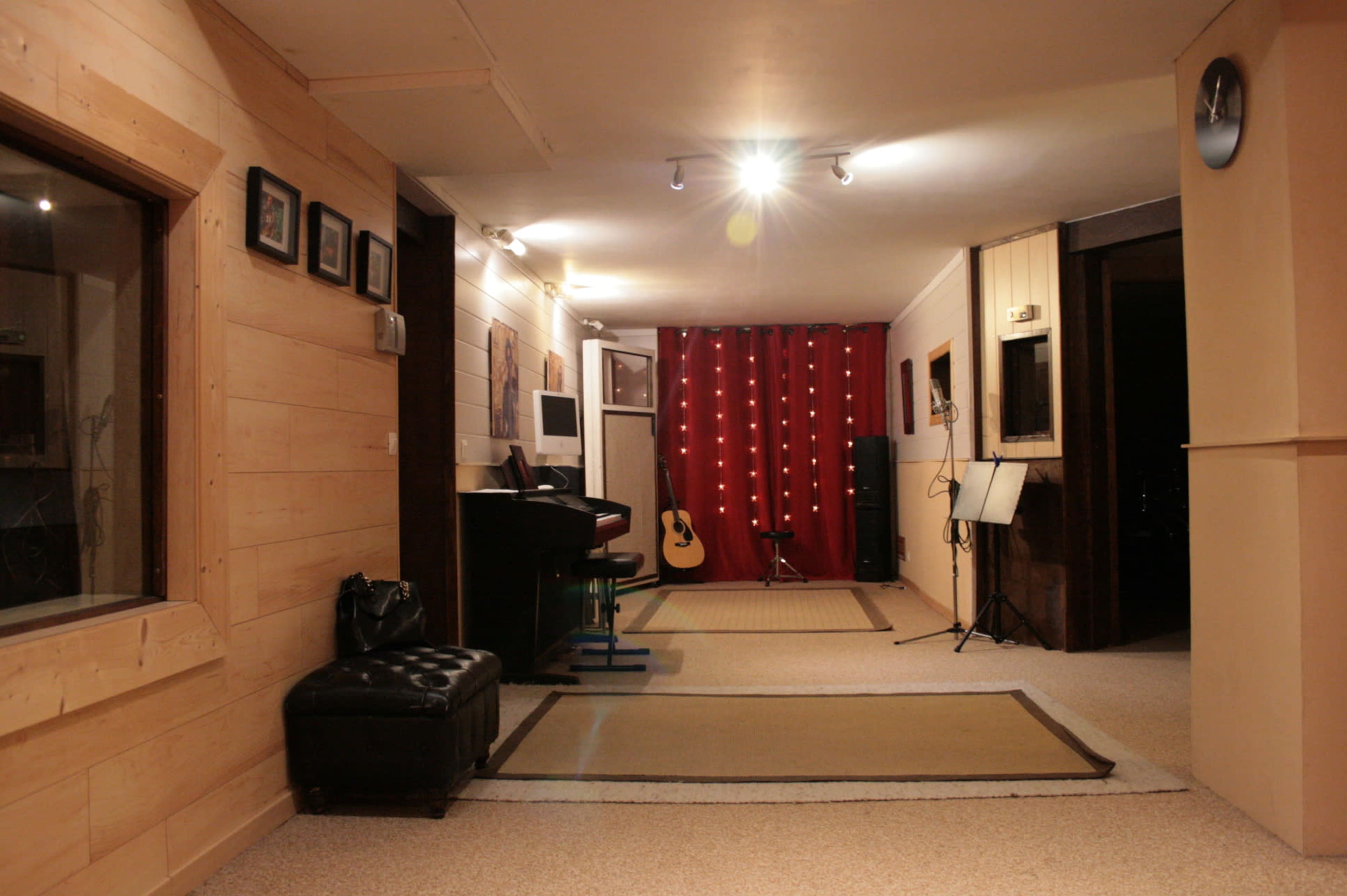 A hallway features wooden paneling, a black piano, an acoustic guitar, and a red curtain adorned with string lights.