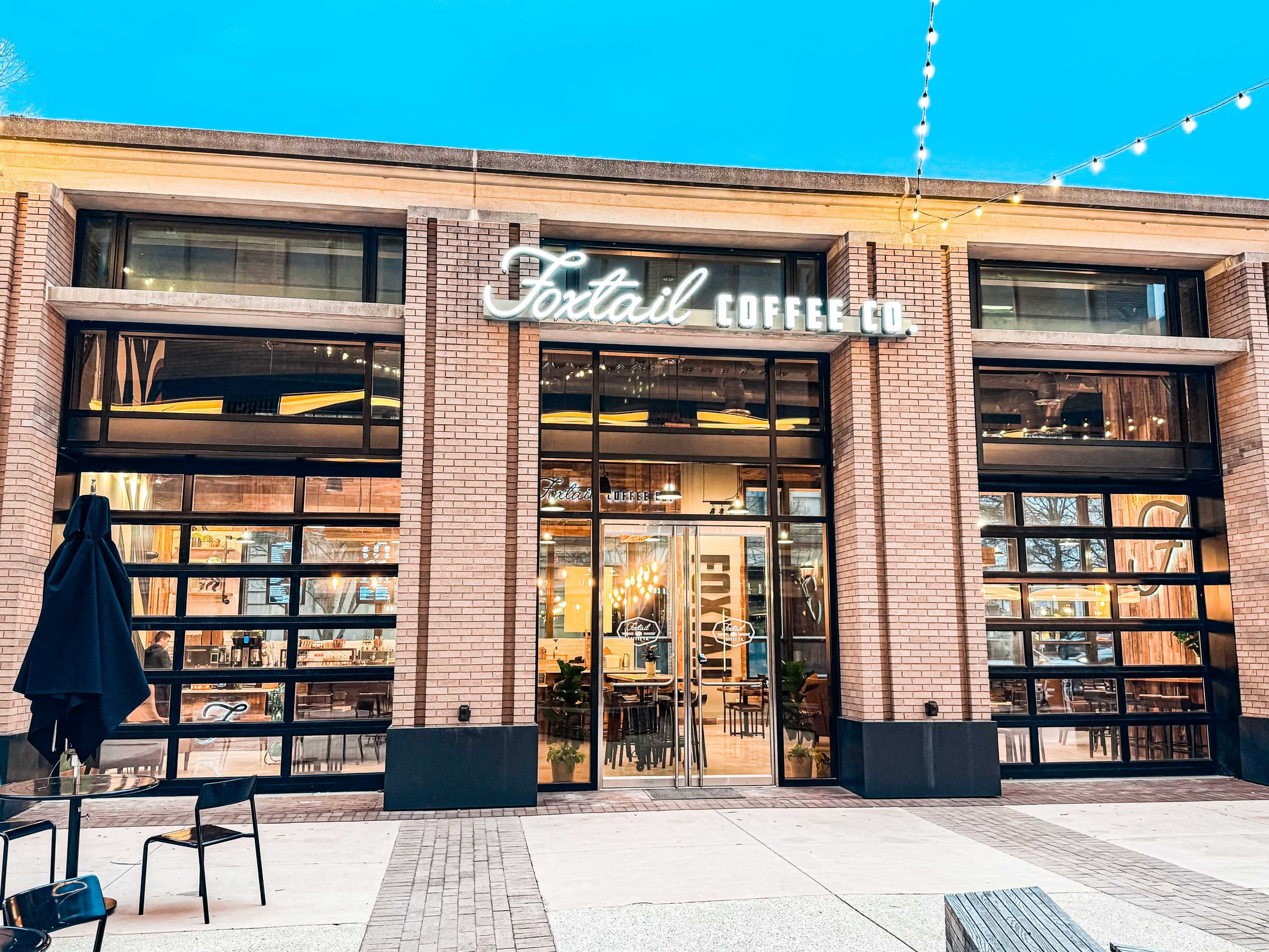 The image shows the exterior of a coffee shop named "Foxtail Coffee Co." with large glass doors and a modern architectural design.