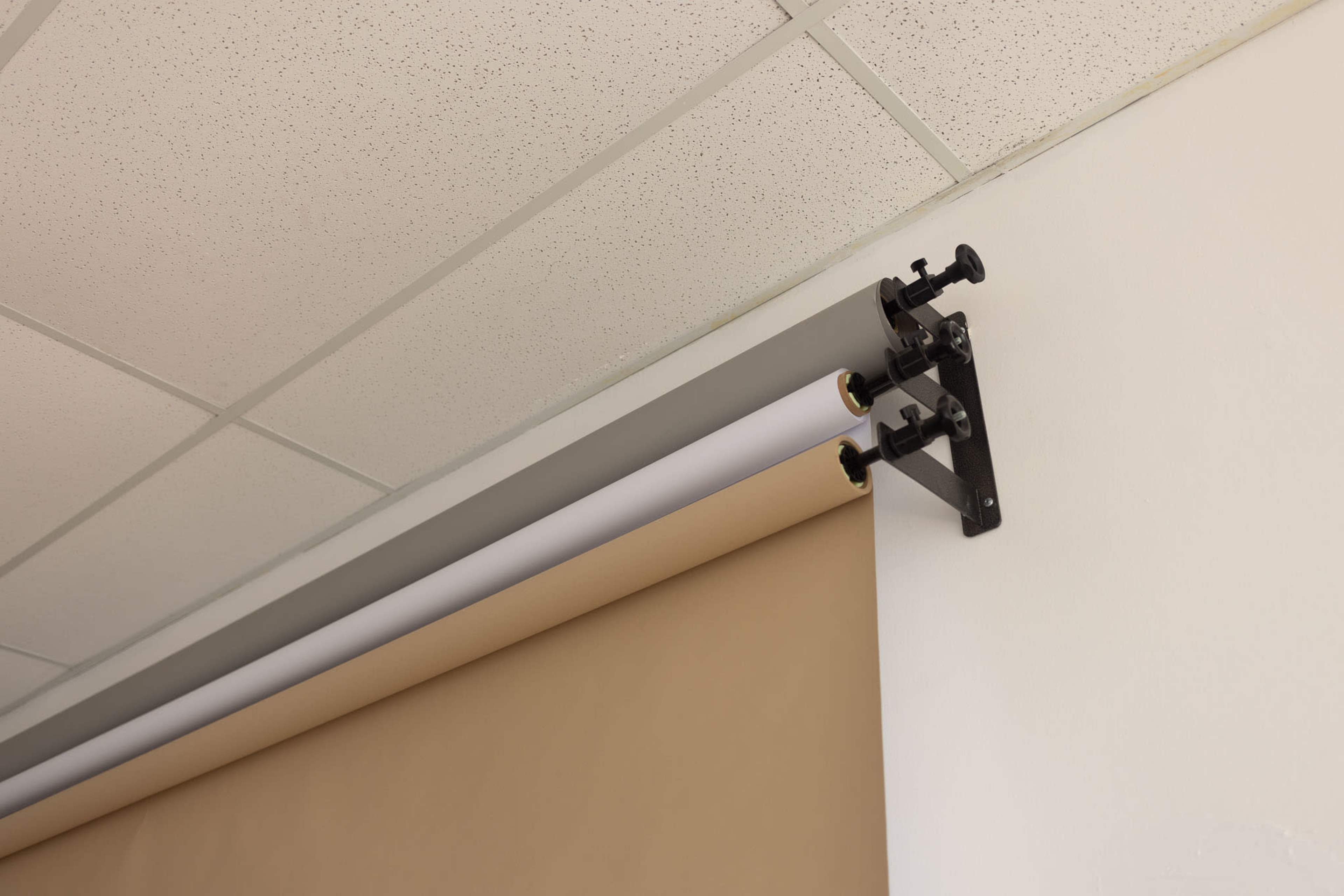 The image shows a mounted fabric roller blind in neutral colors attached to a wall and ceiling.