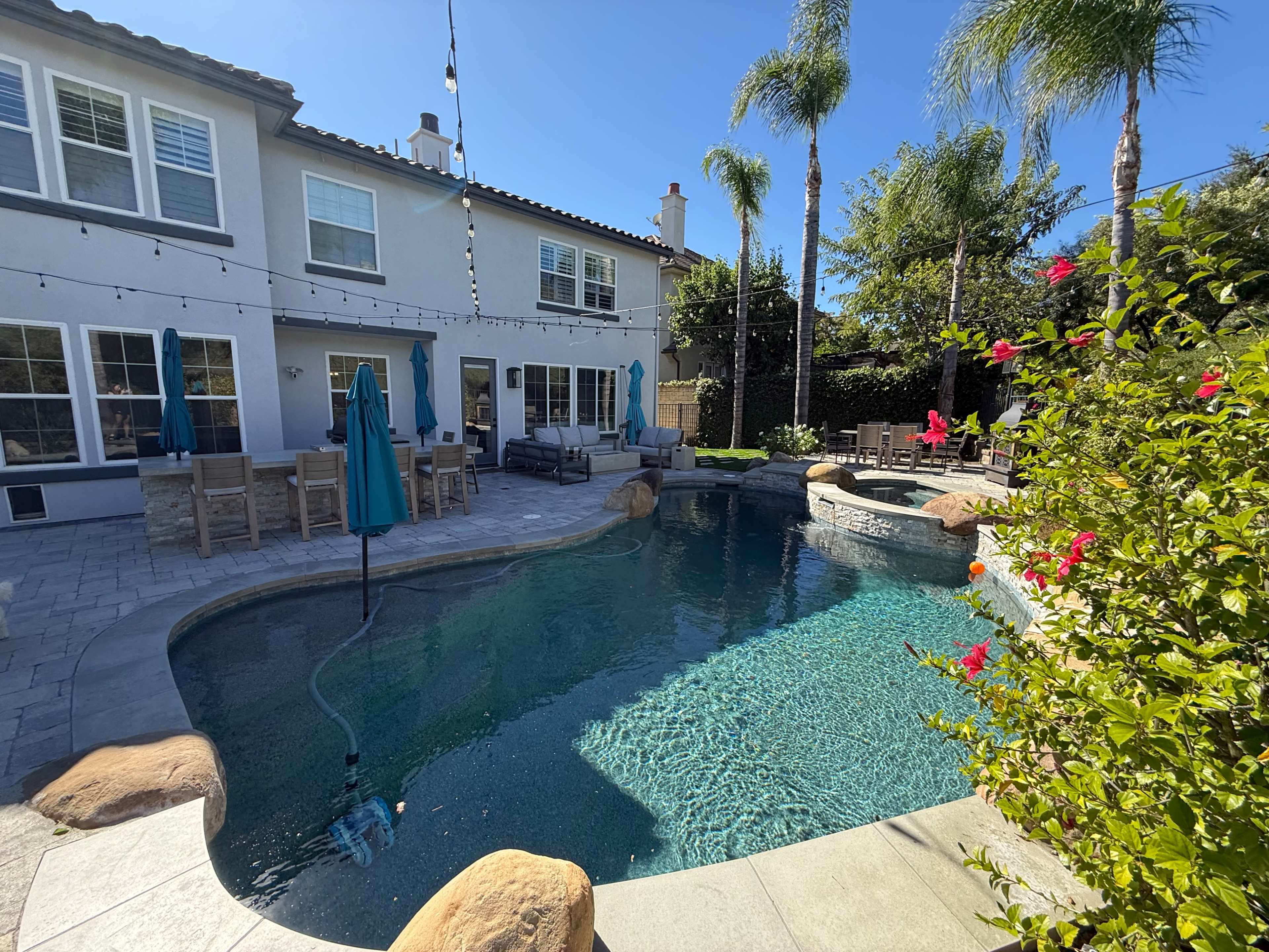 Discover a hidden gem — Surrounded by green hills and palm trees, this tranquil backyard retreat offers a saltwater pool, jacuzzi, and elegant entertaining area. Perfect for celebrations, photoshoots, or relaxing under twinkling string lights. 💦🌴 Image in Stevenson Ranch, Valencia, CA