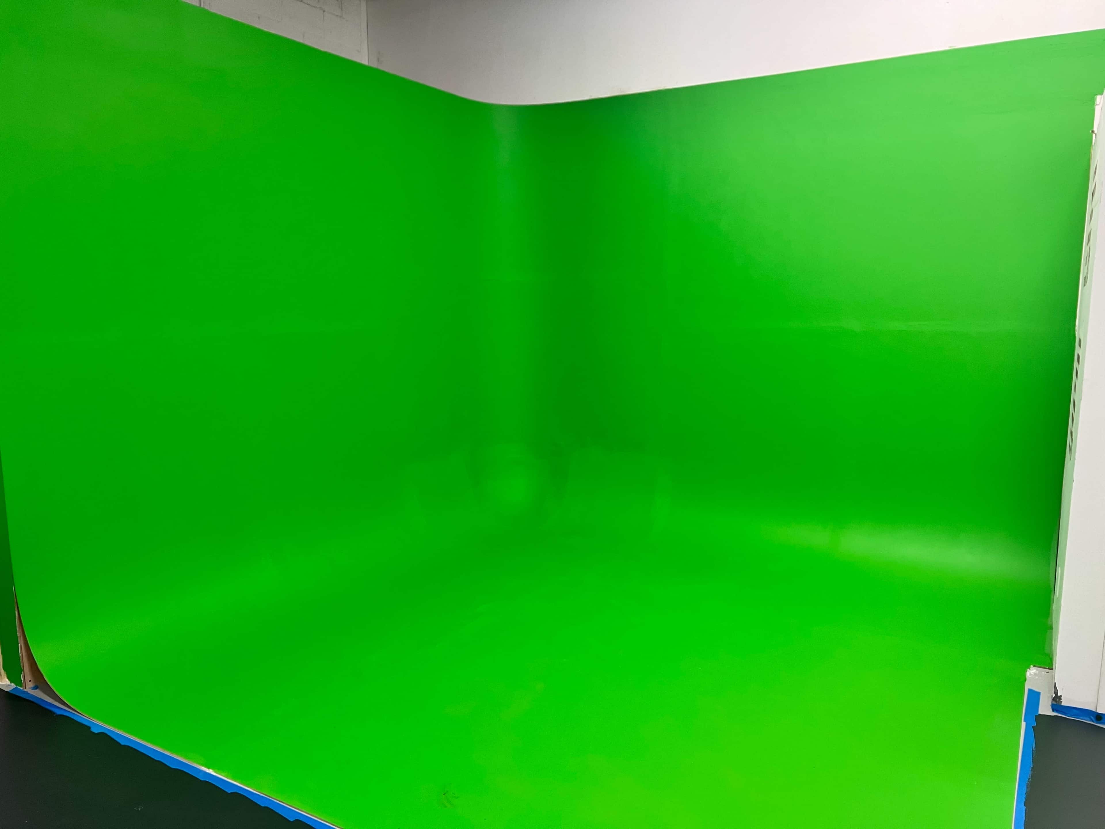 A bright green, seamless studio backdrop set up in a photo studio.