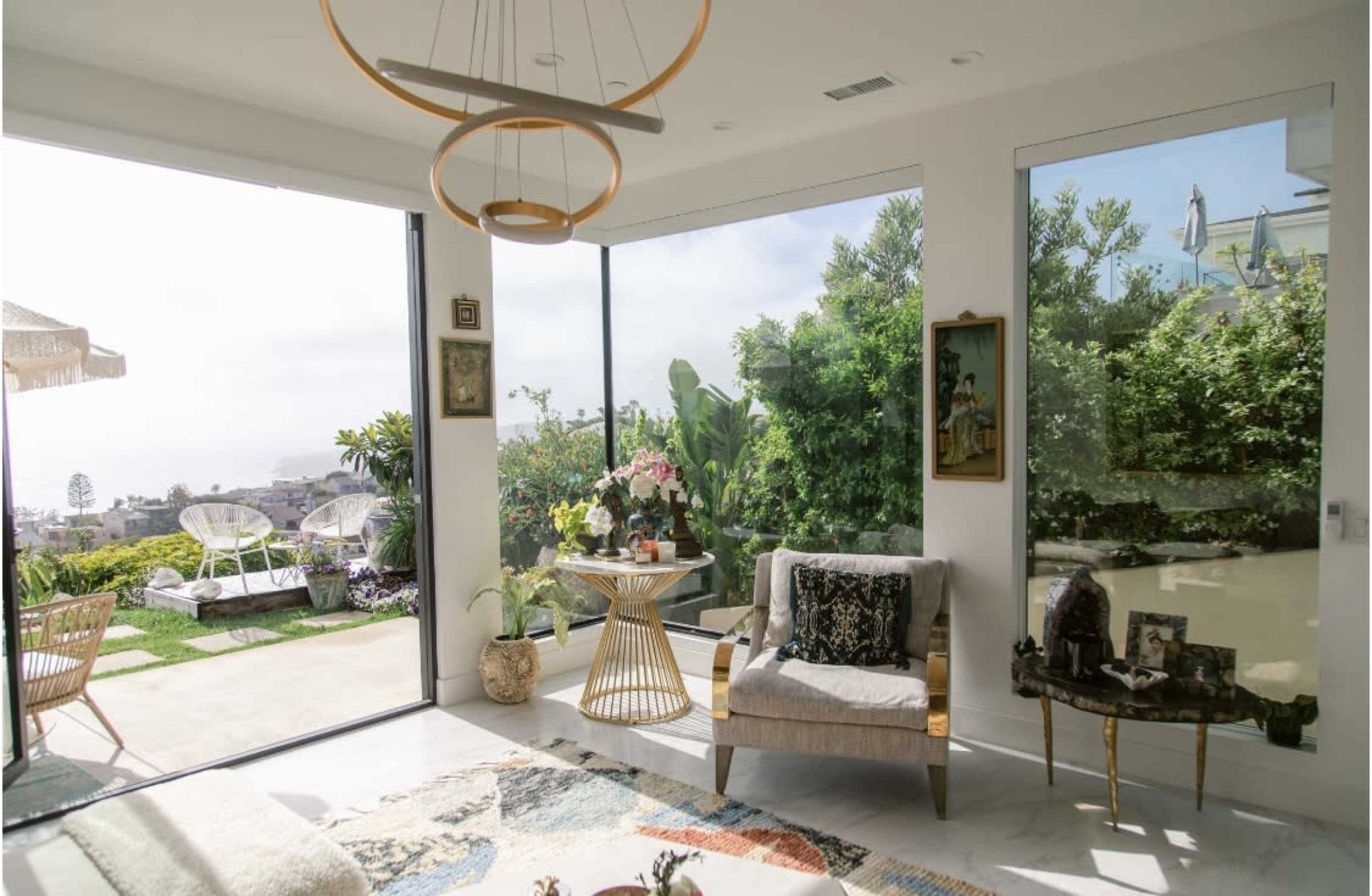 The room features large glass windows overlooking a landscaped garden, with modern furniture arranged around a circular table.