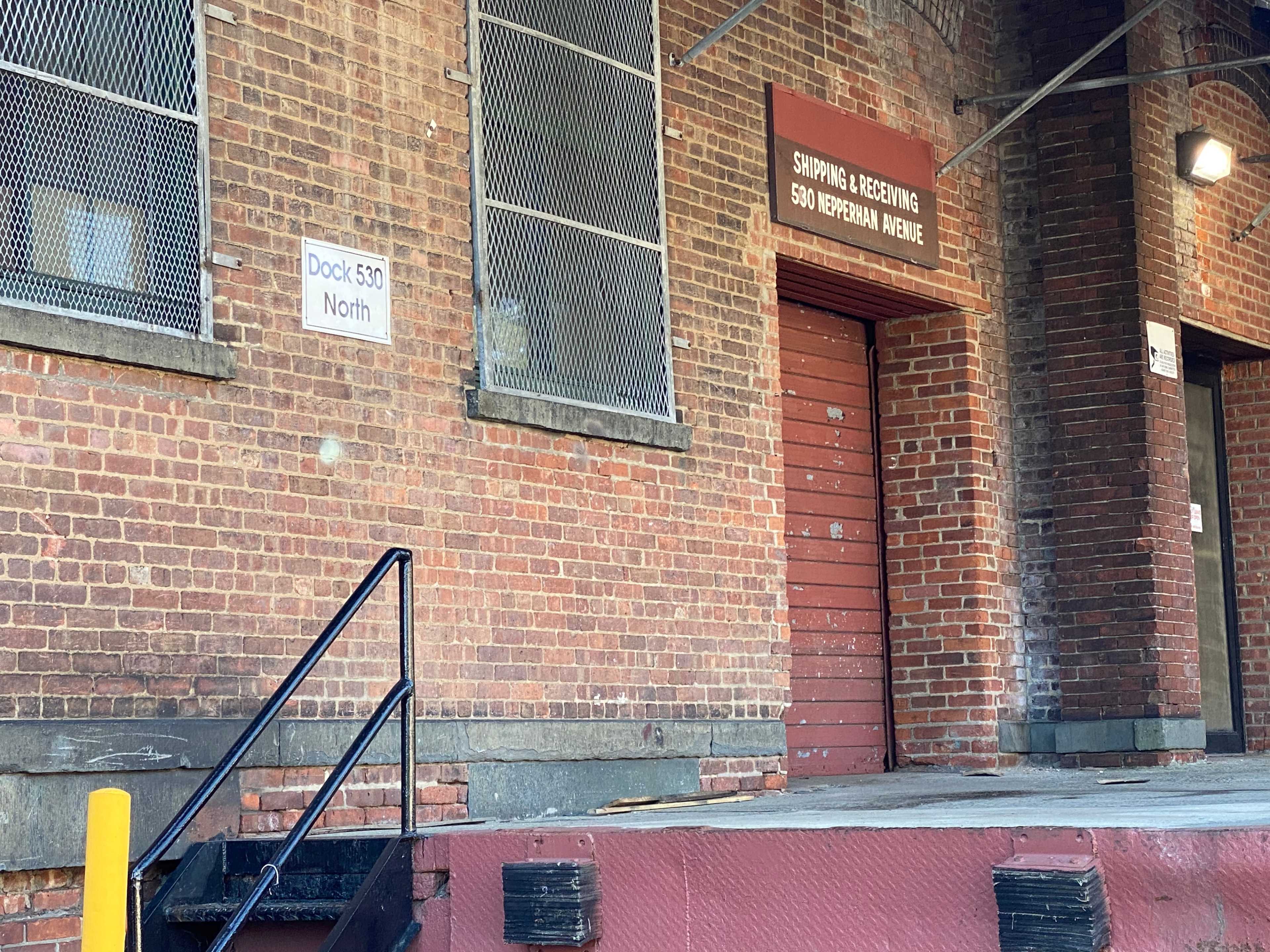 The image shows the exterior of a brick warehouse with a loading dock and a door labeled “Shipping & Receiving.”