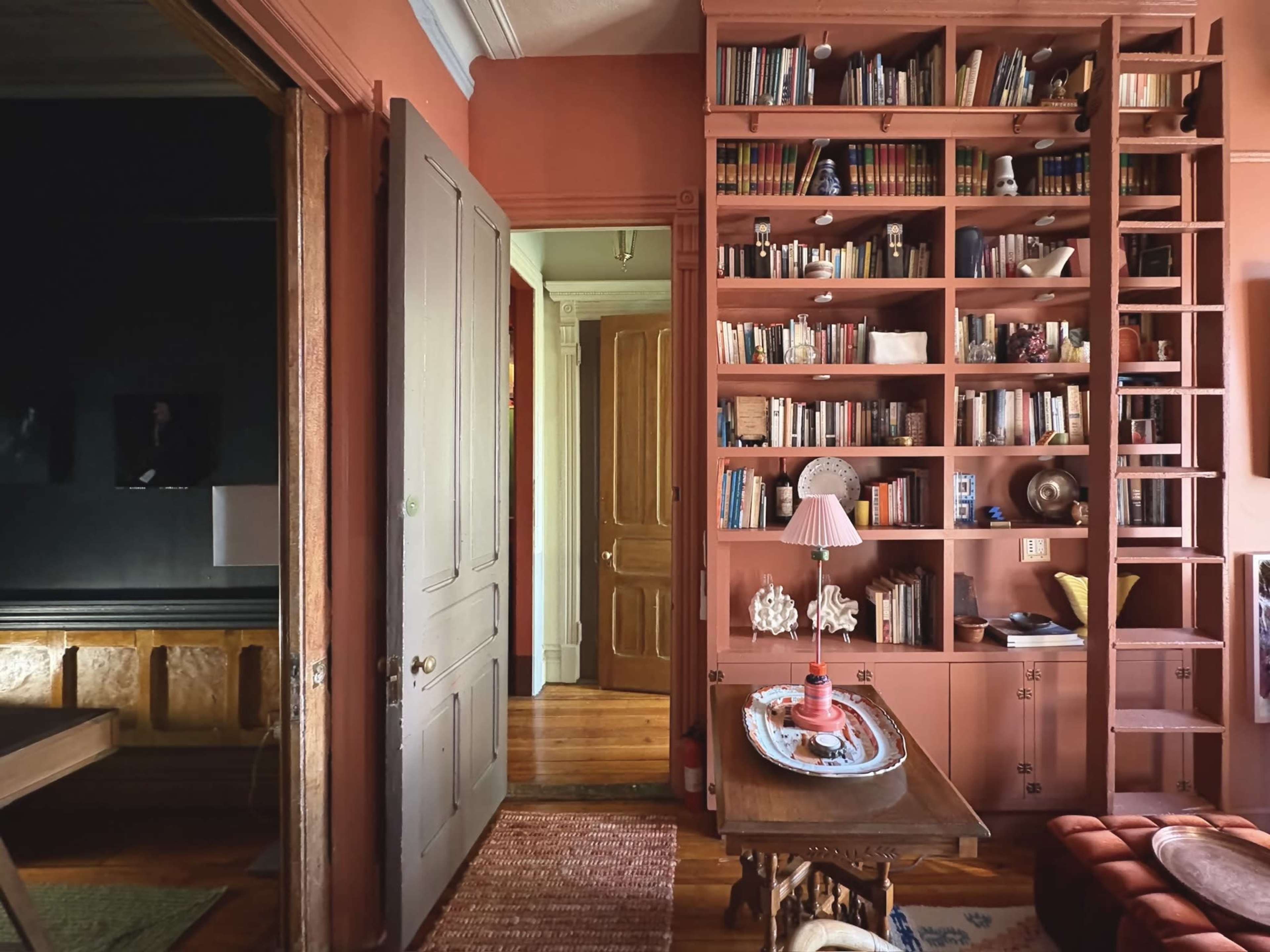 A colorful room features a bookshelf filled with books, a wooden table, and a doorway leading to another space.
