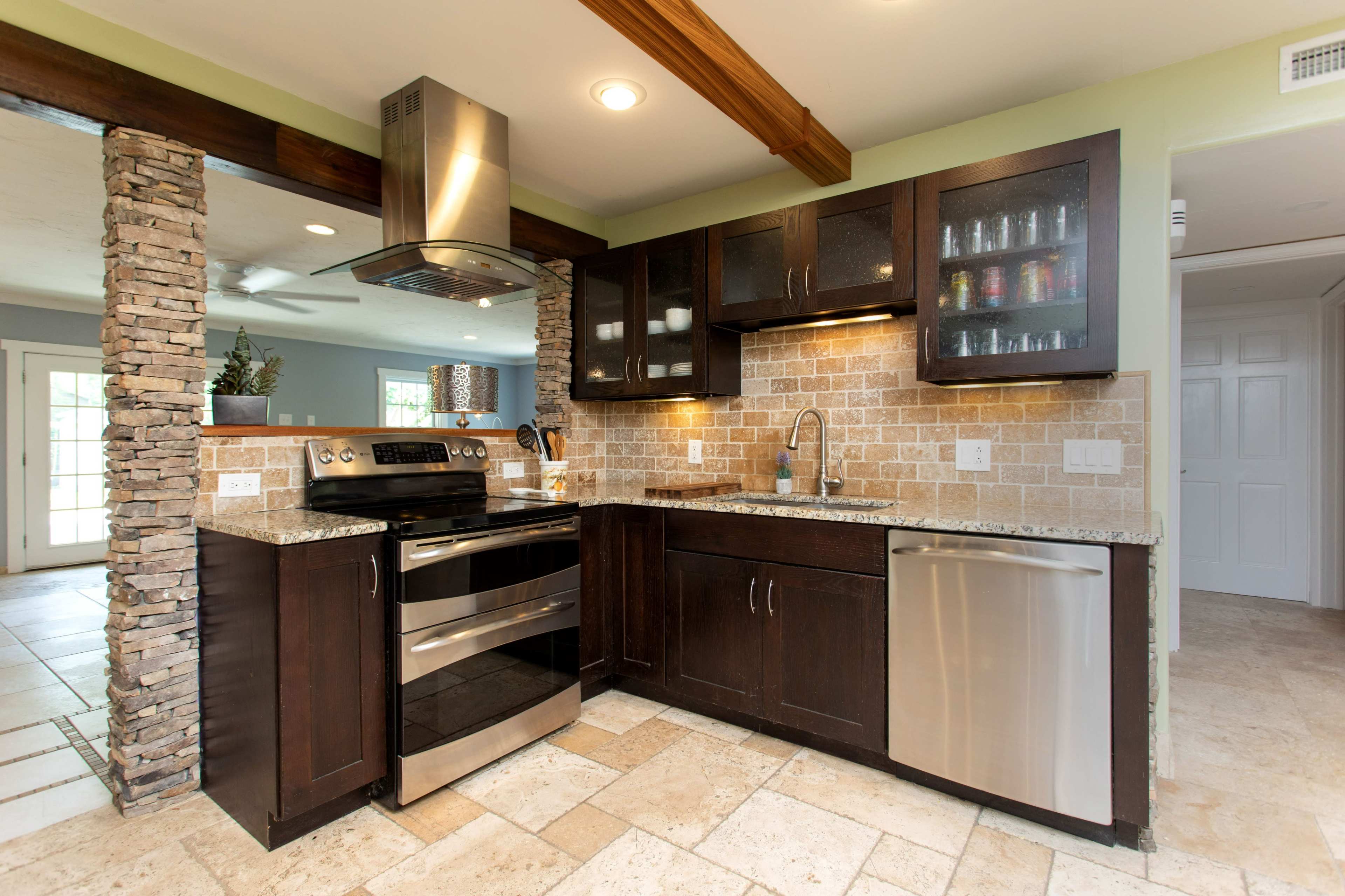 The kitchen features dark wood cabinetry, stainless steel appliances, and a stone accent wall with a tiled backsplash.