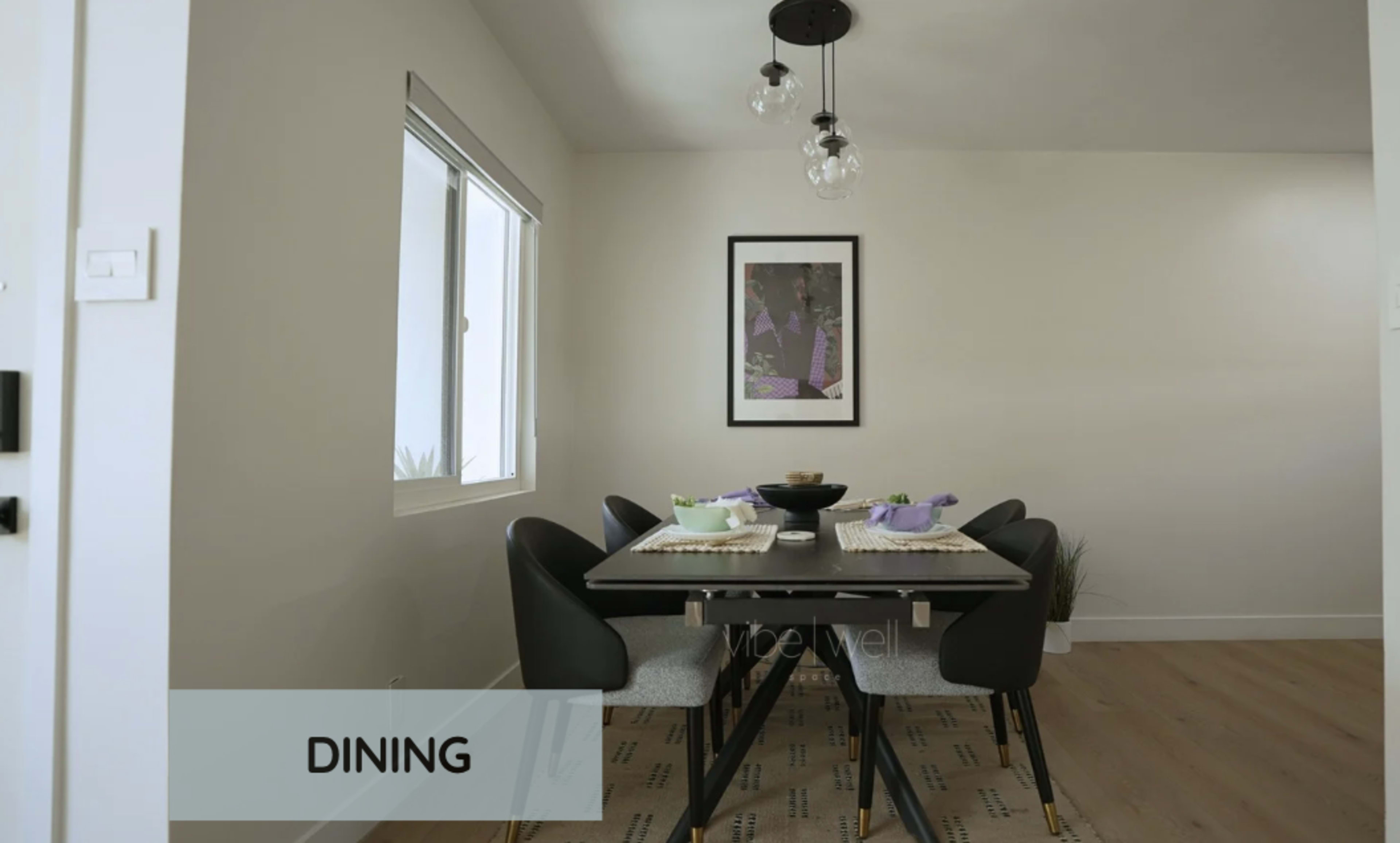 A dining area features a table set for six with modern chairs, a bowl in the center, and framed artwork on the wall.