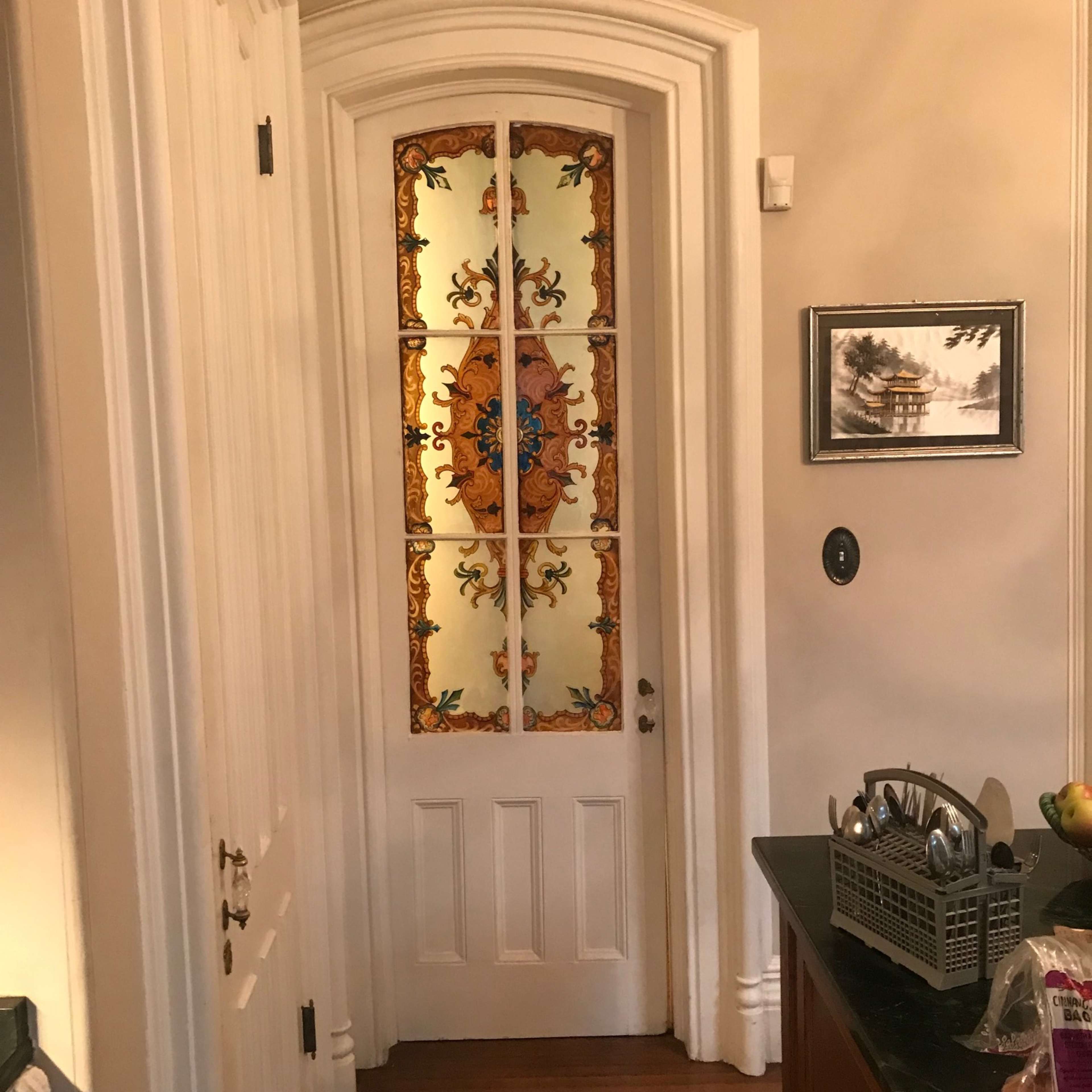A decorative door with stained glass panels featuring floral designs, leading into another room.