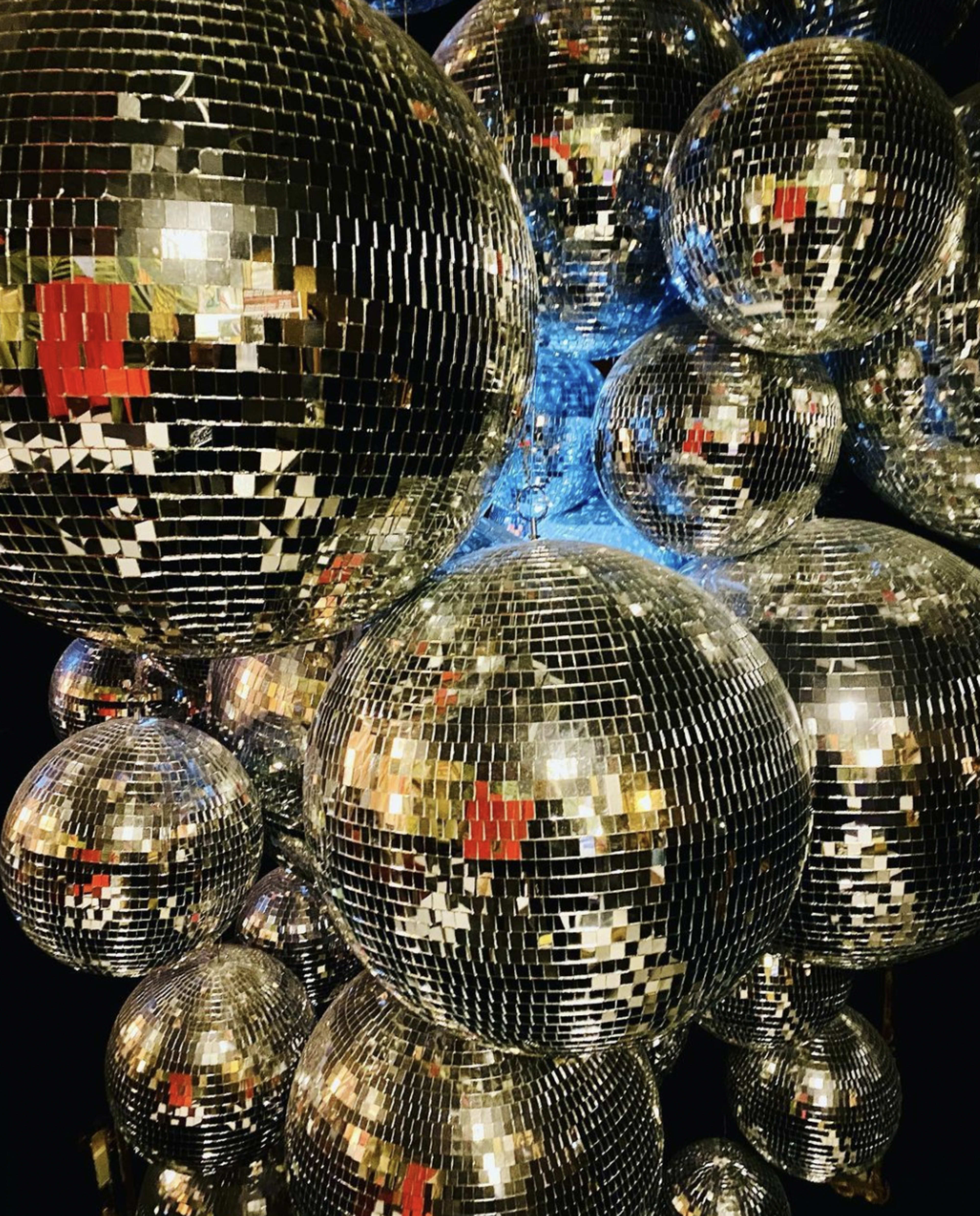 A cluster of shiny disco balls reflecting light in various directions.