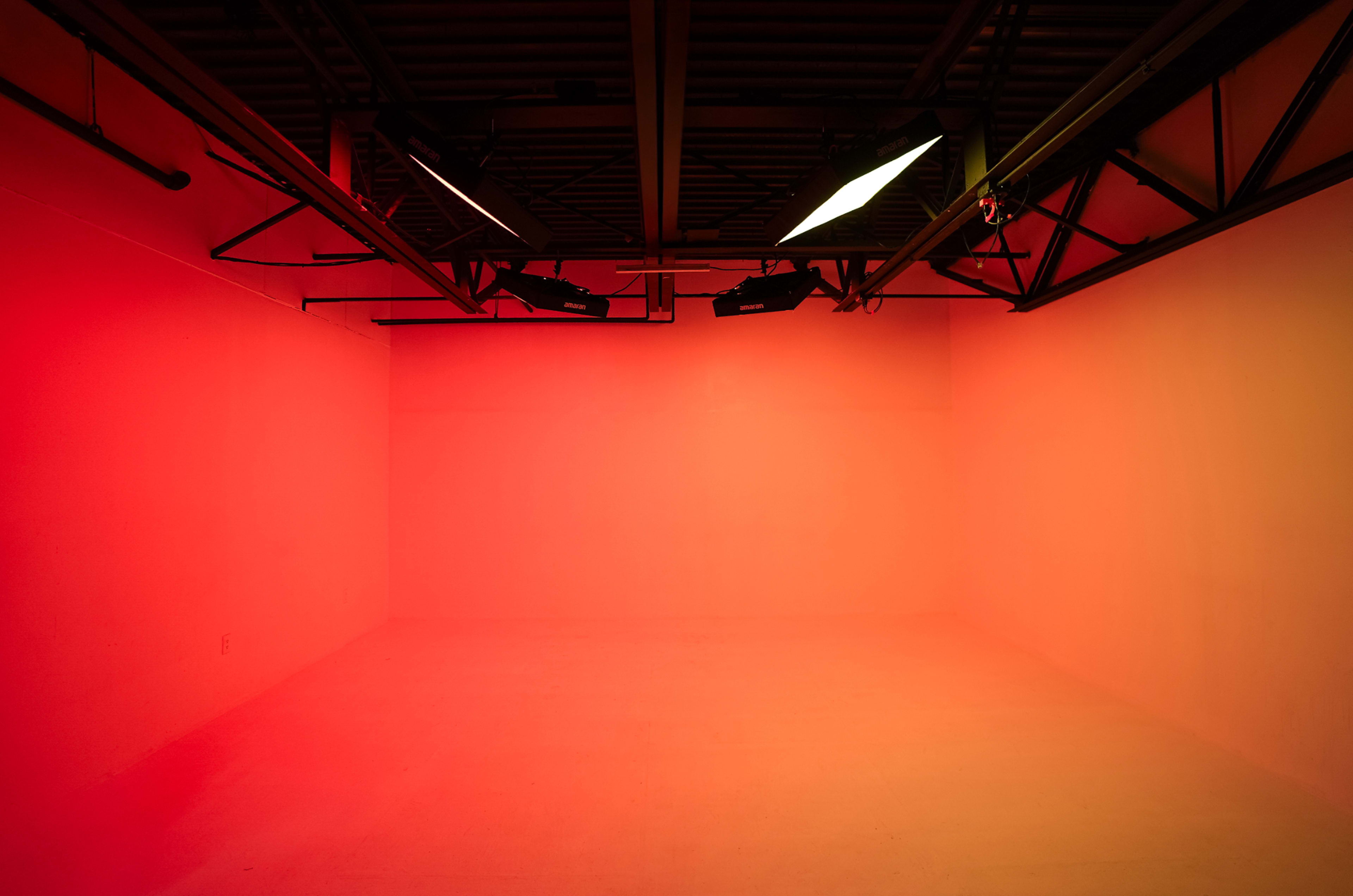 The image shows an empty room with red lighting and a ceiling structure of beams and lights.
