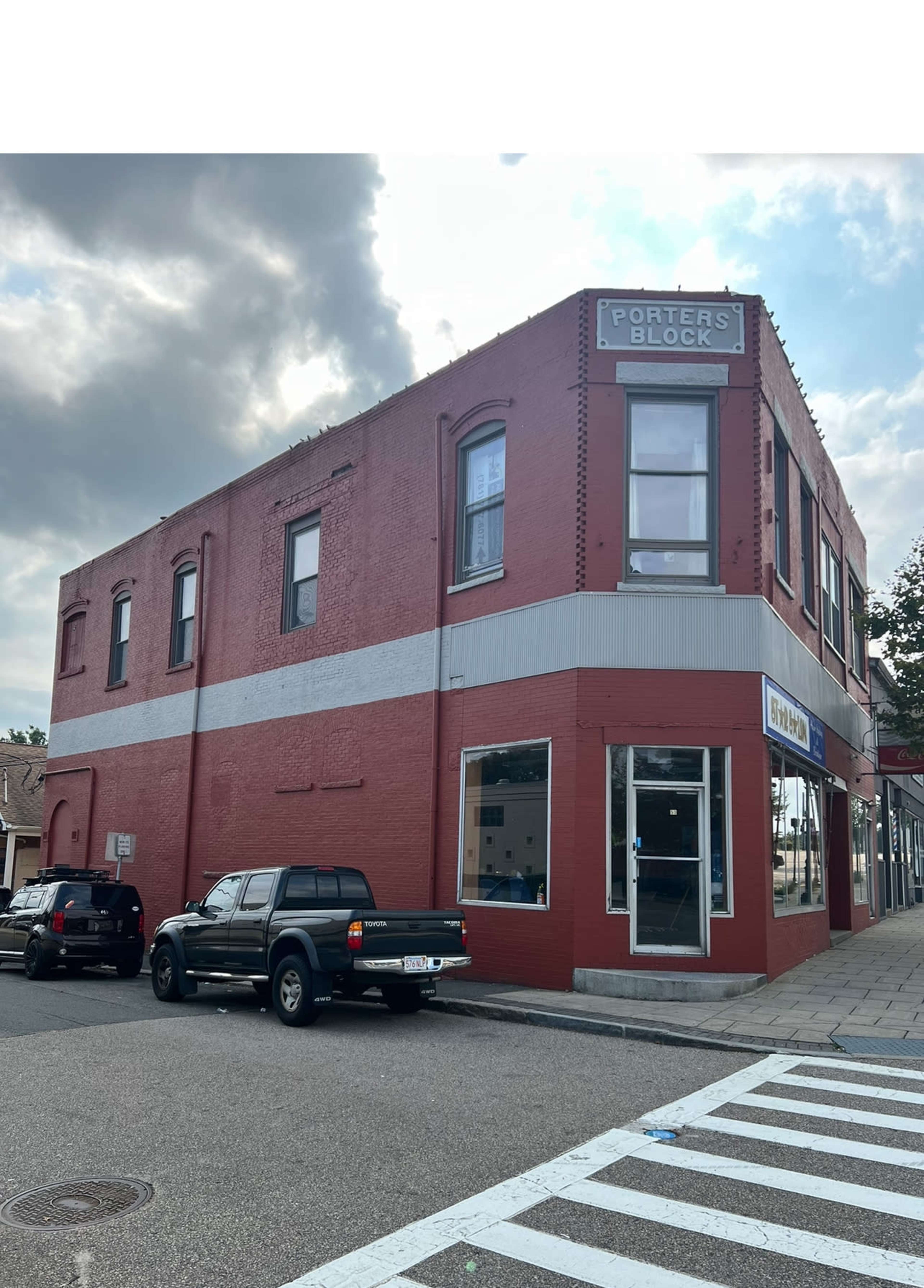 The image shows a red brick building with the sign "Porter's Block" on the upper corner, situated at the intersection of two streets with parked vehicles nearby.