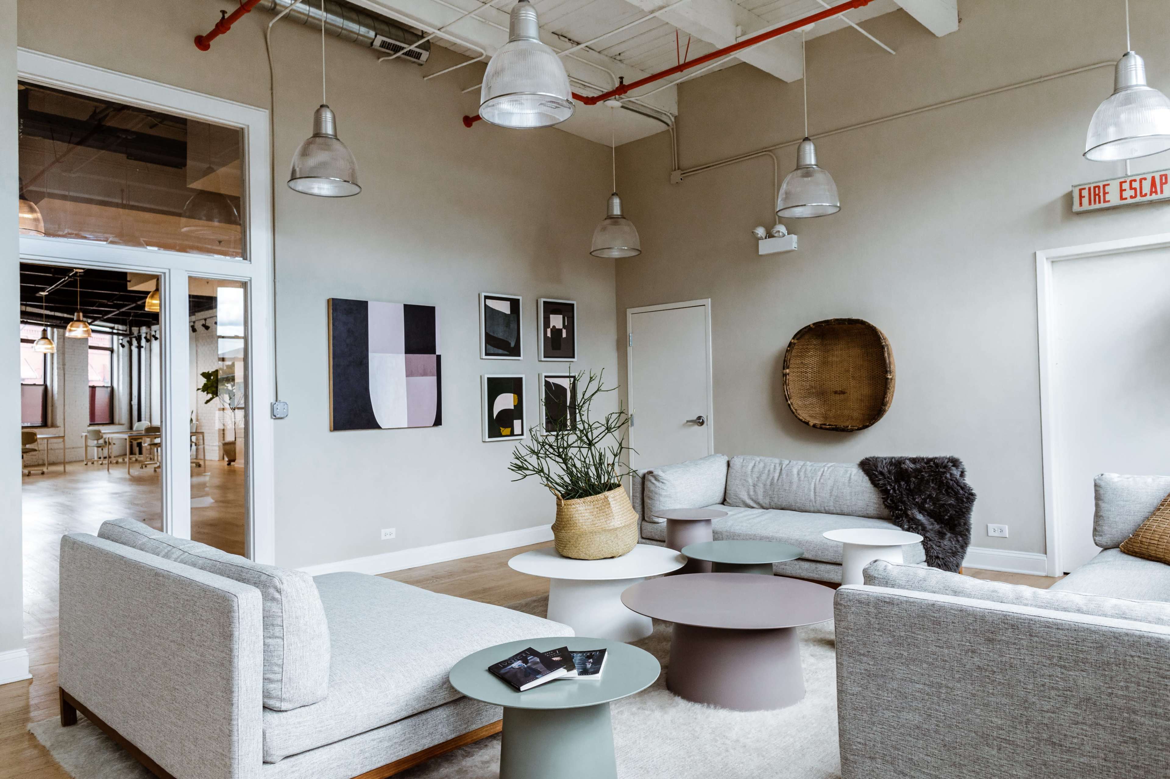 A modern lounge area with gray sofas, round tables, and minimalist artwork on the walls.