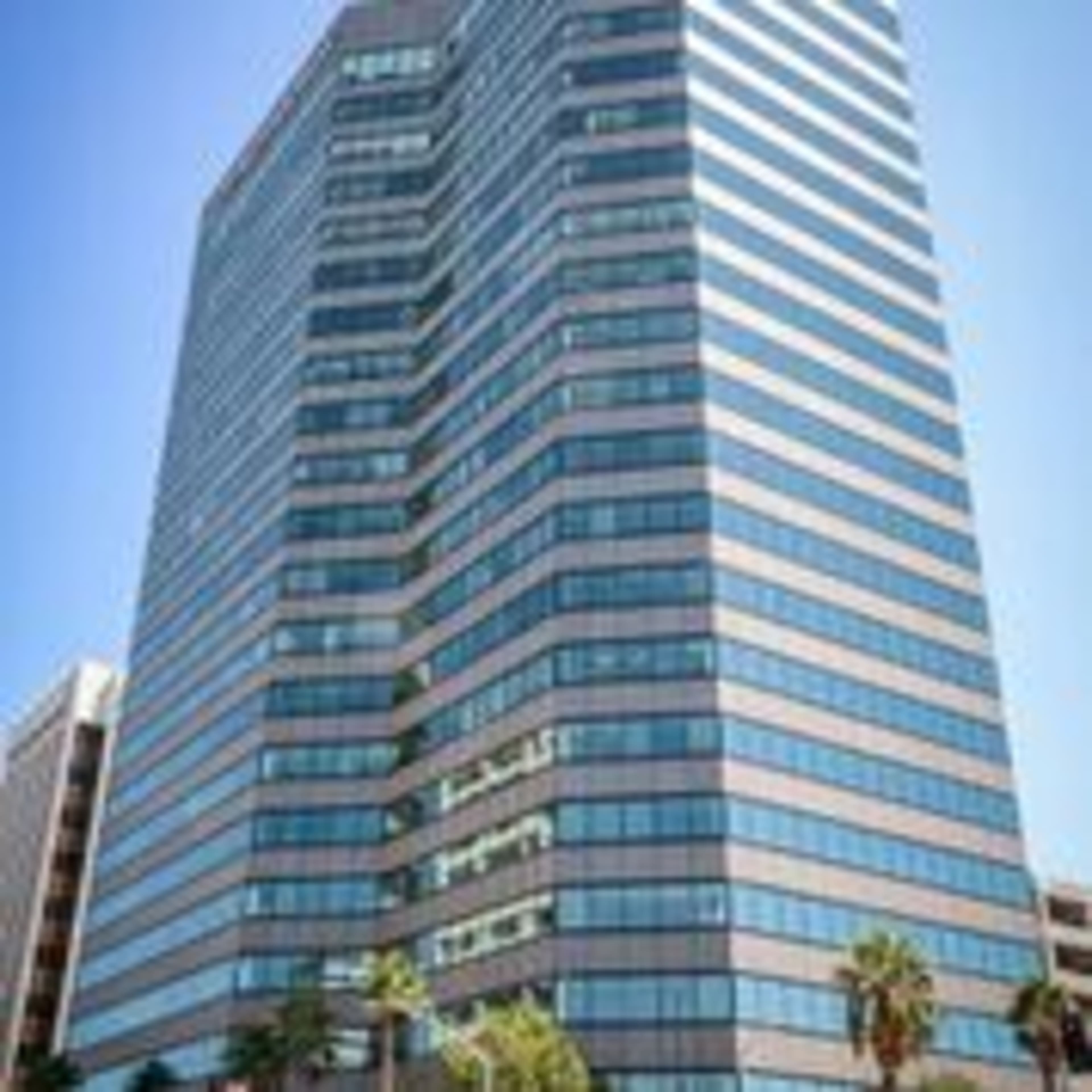 A tall office building features a modern design with numerous glass windows and a geometric facade.