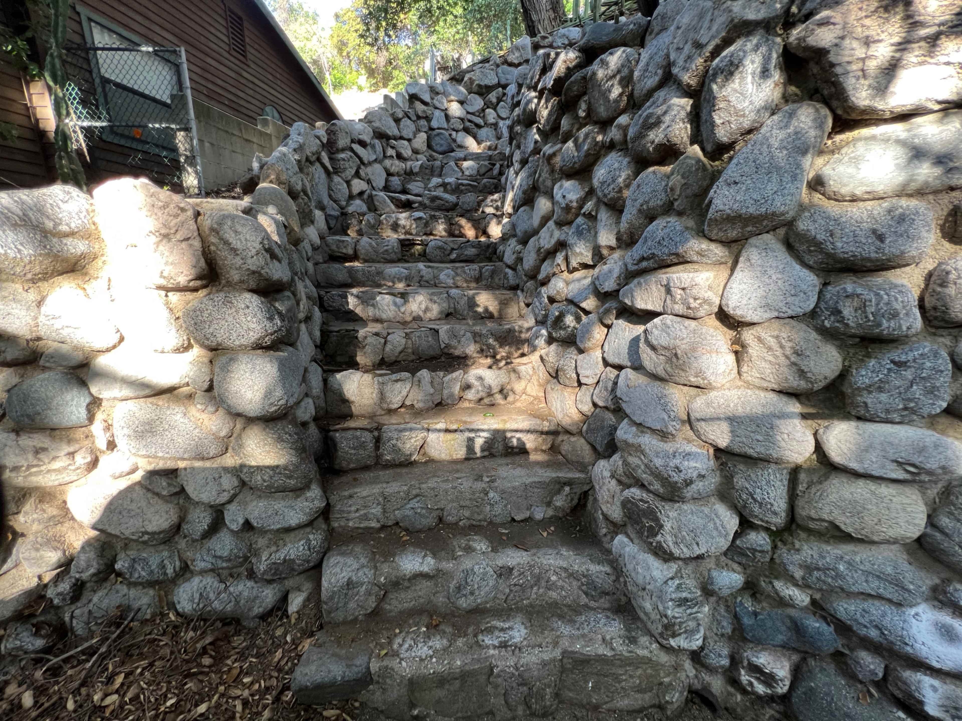 A set of stone steps leading upward, flanked by a wall of unevenly shaped stones.