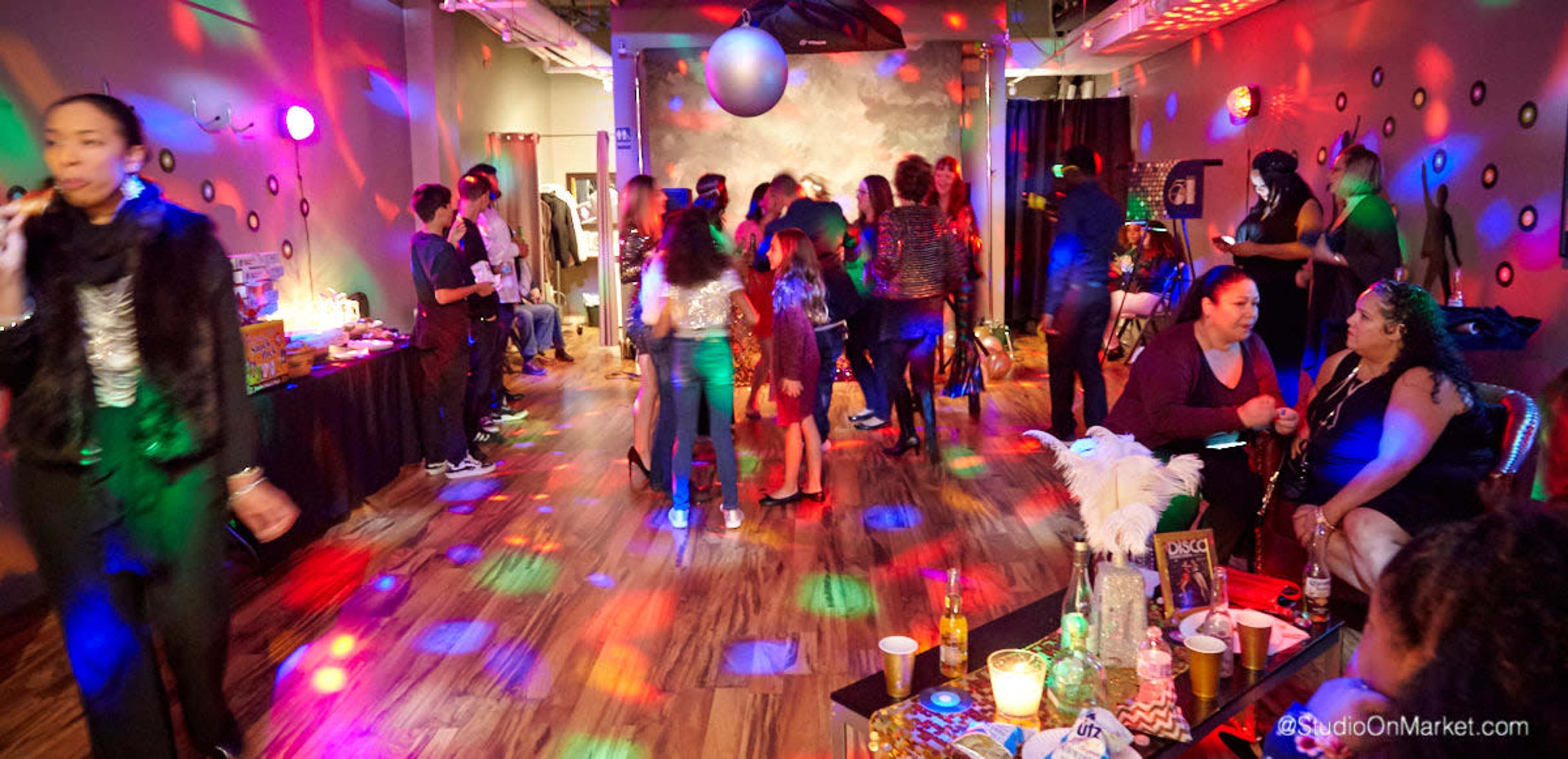 A lively indoor party scene features people dancing and socializing under colorful disco lights.