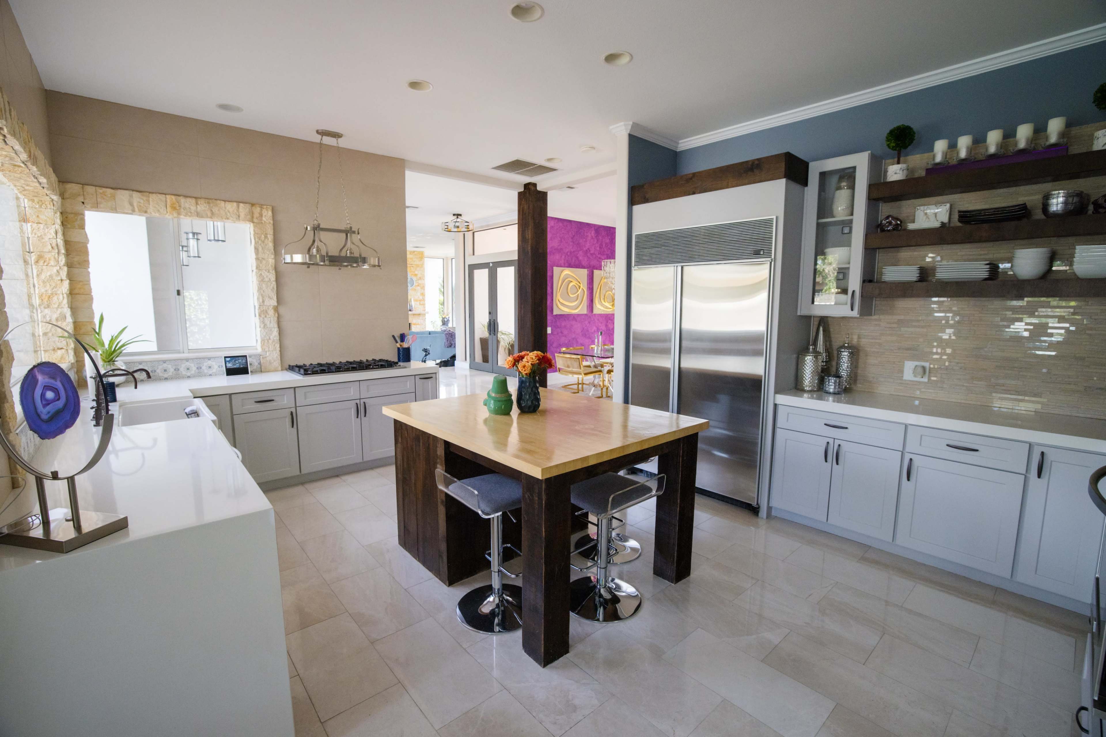 A modern kitchen featuring a central wooden island, stainless steel appliances, and a combination of light and dark cabinetry.