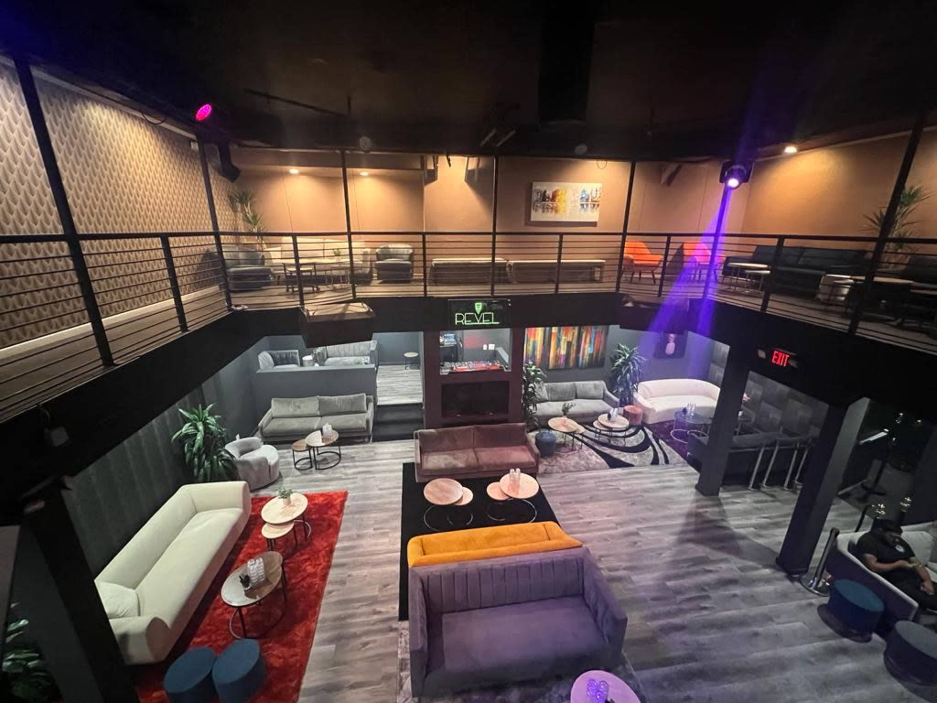 A spacious lounge area with multiple seating arrangements on two levels, featuring sofas, tables, and decorative plants.