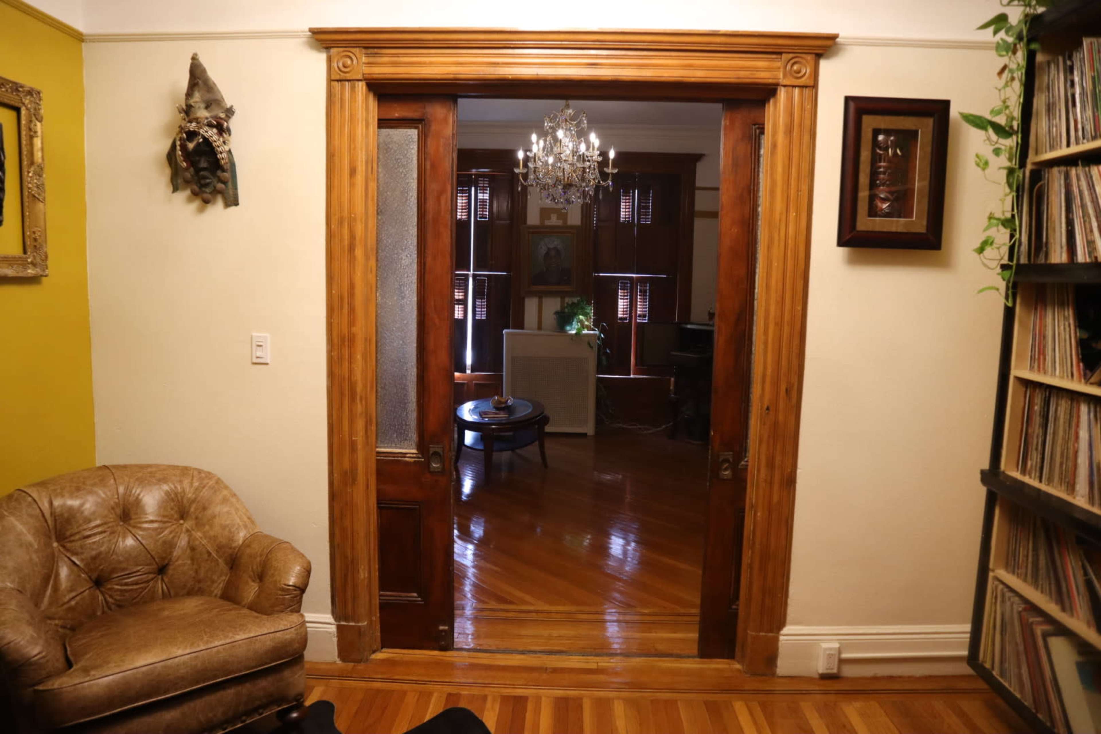 A wooden arched doorway leads to a room with a chandelier and furniture arrangements visible in the background.