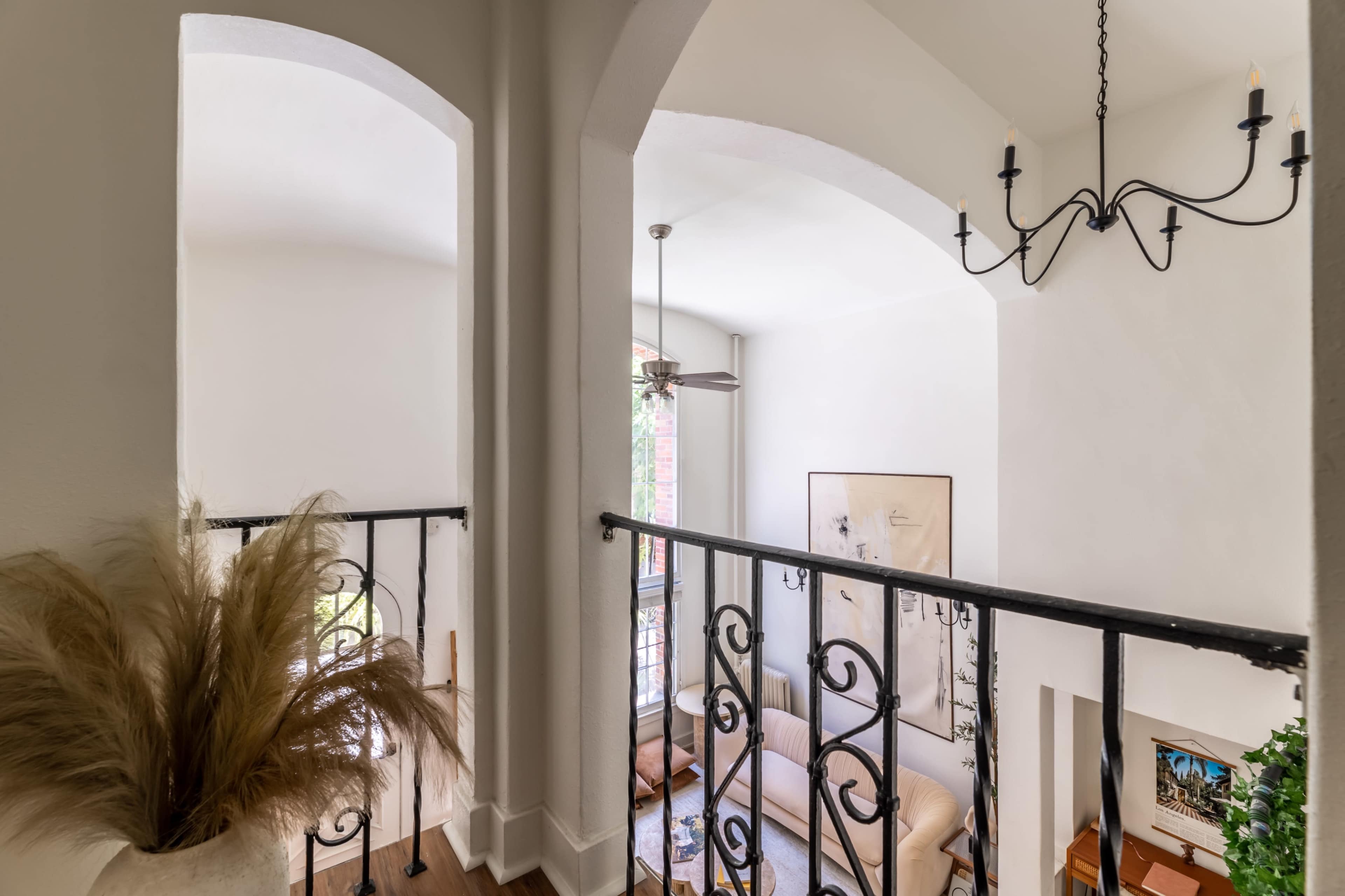 A view from a balcony overlooking a softly lit living area with a couch and a ceiling fan.