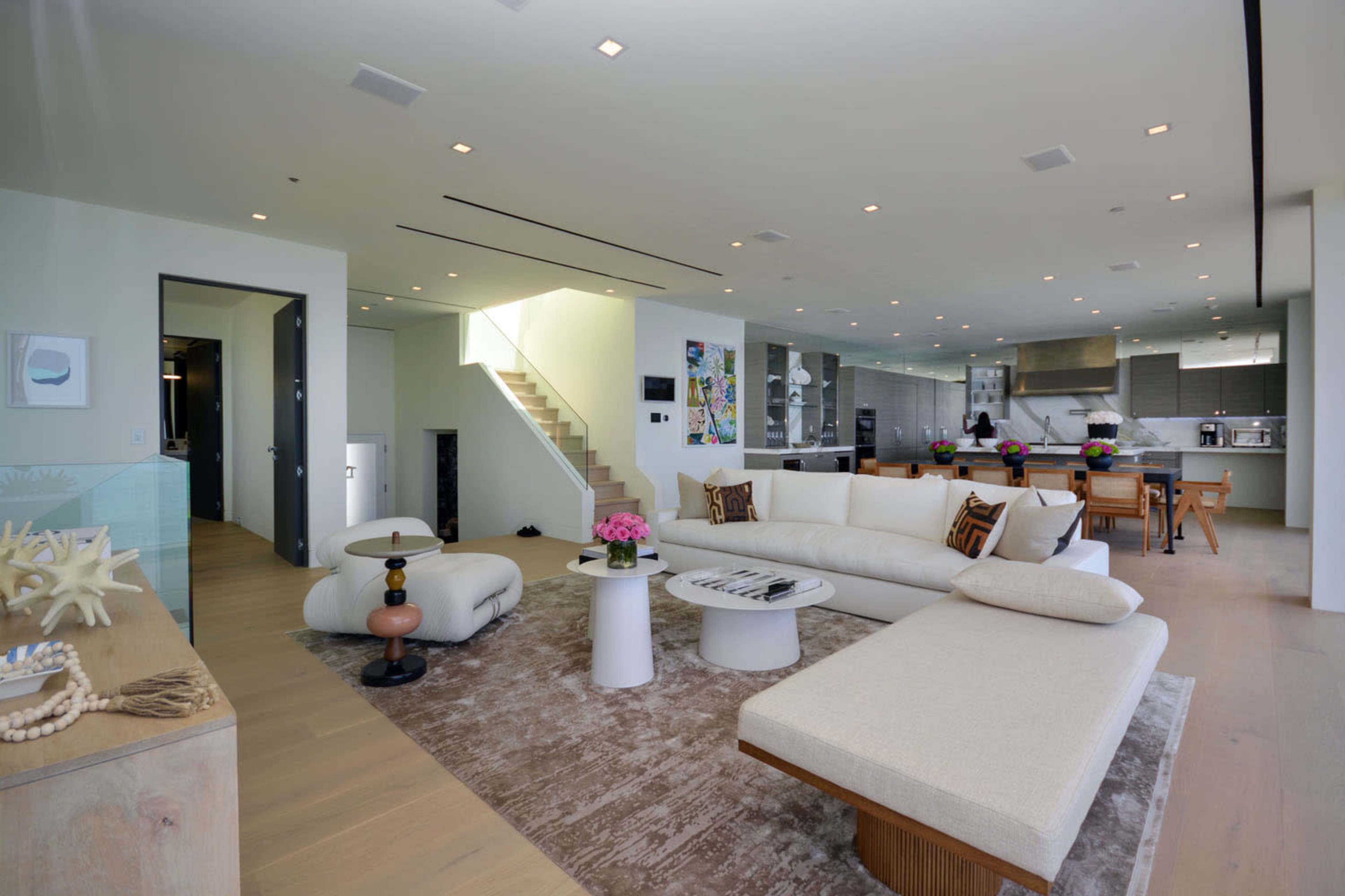 A modern living room with a large sectional sofa, a coffee table, and an open kitchen area visible in the background.
