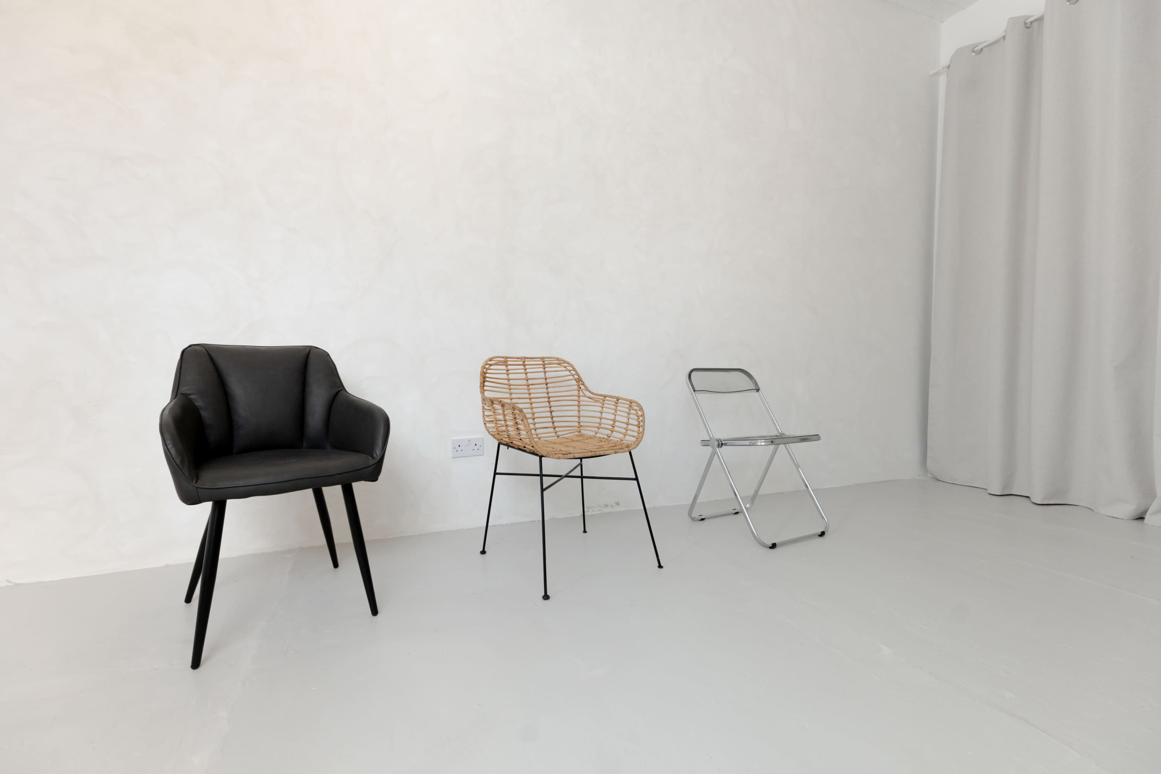 The image shows three chairs of different styles placed against a plain, light-colored wall.