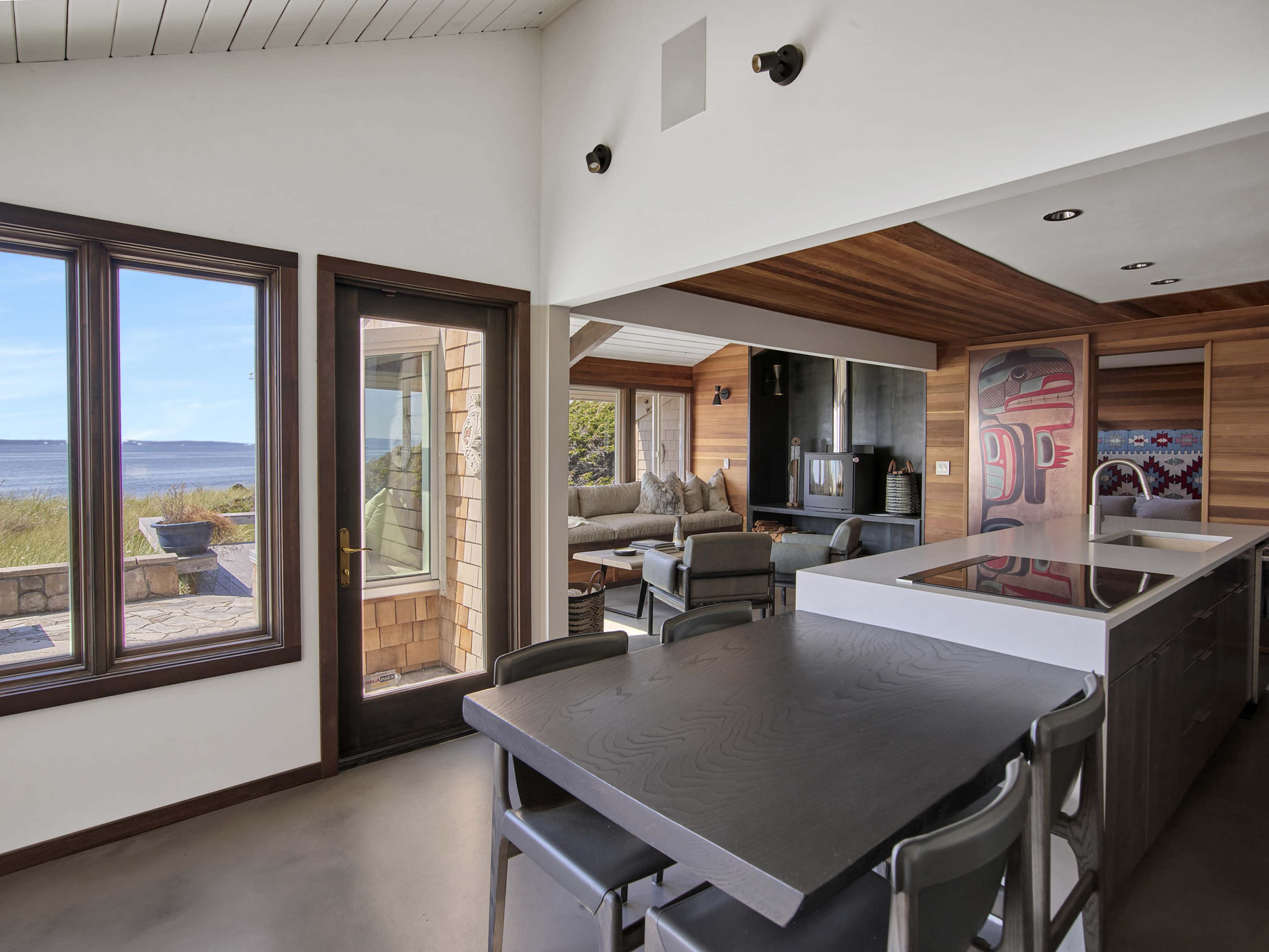 A modern kitchen and living area with large windows overlooking a coastal landscape.