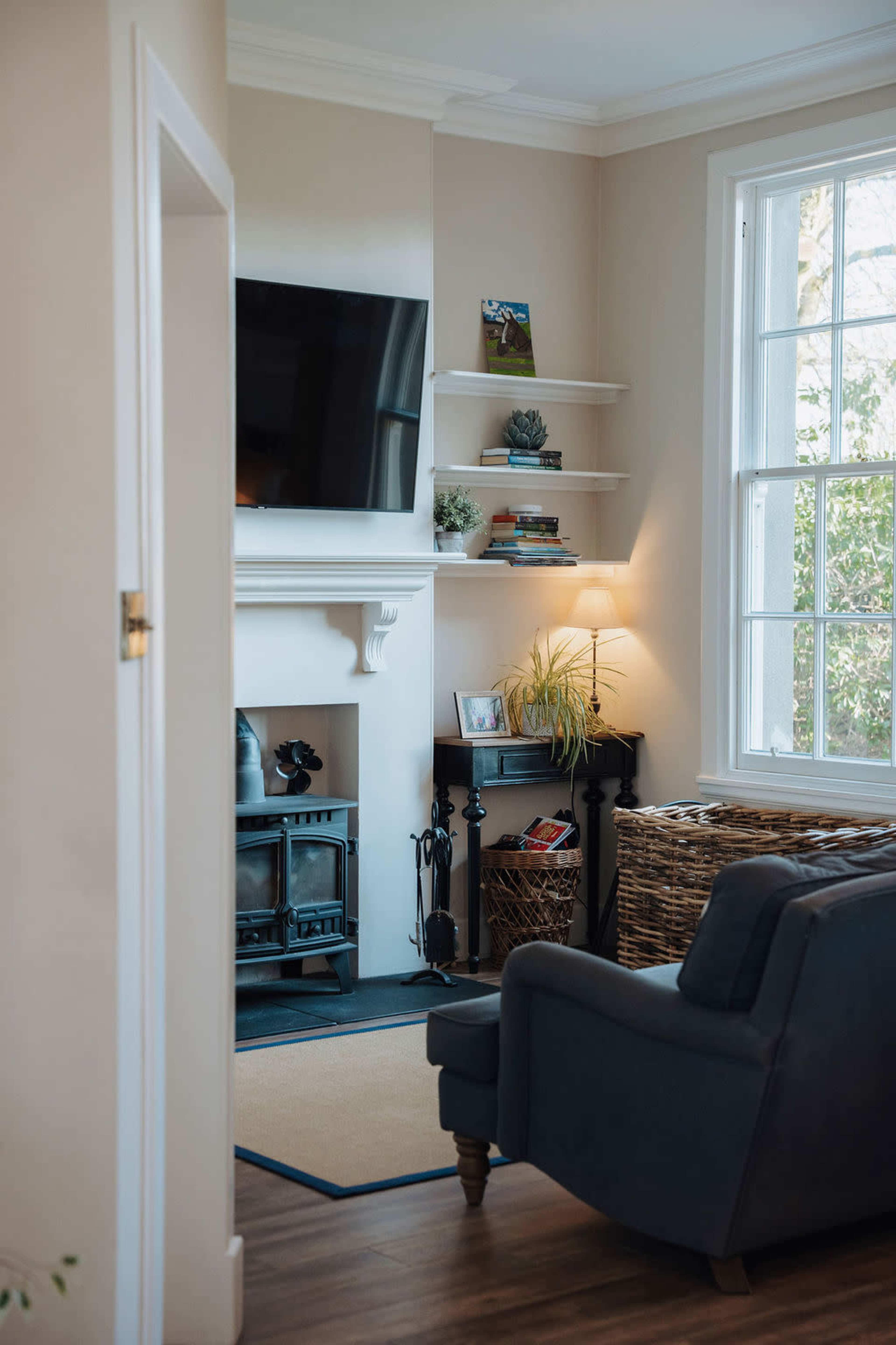 The image shows a living room with a mounted television, a fireplace, built-in shelves, and a comfortable armchair.