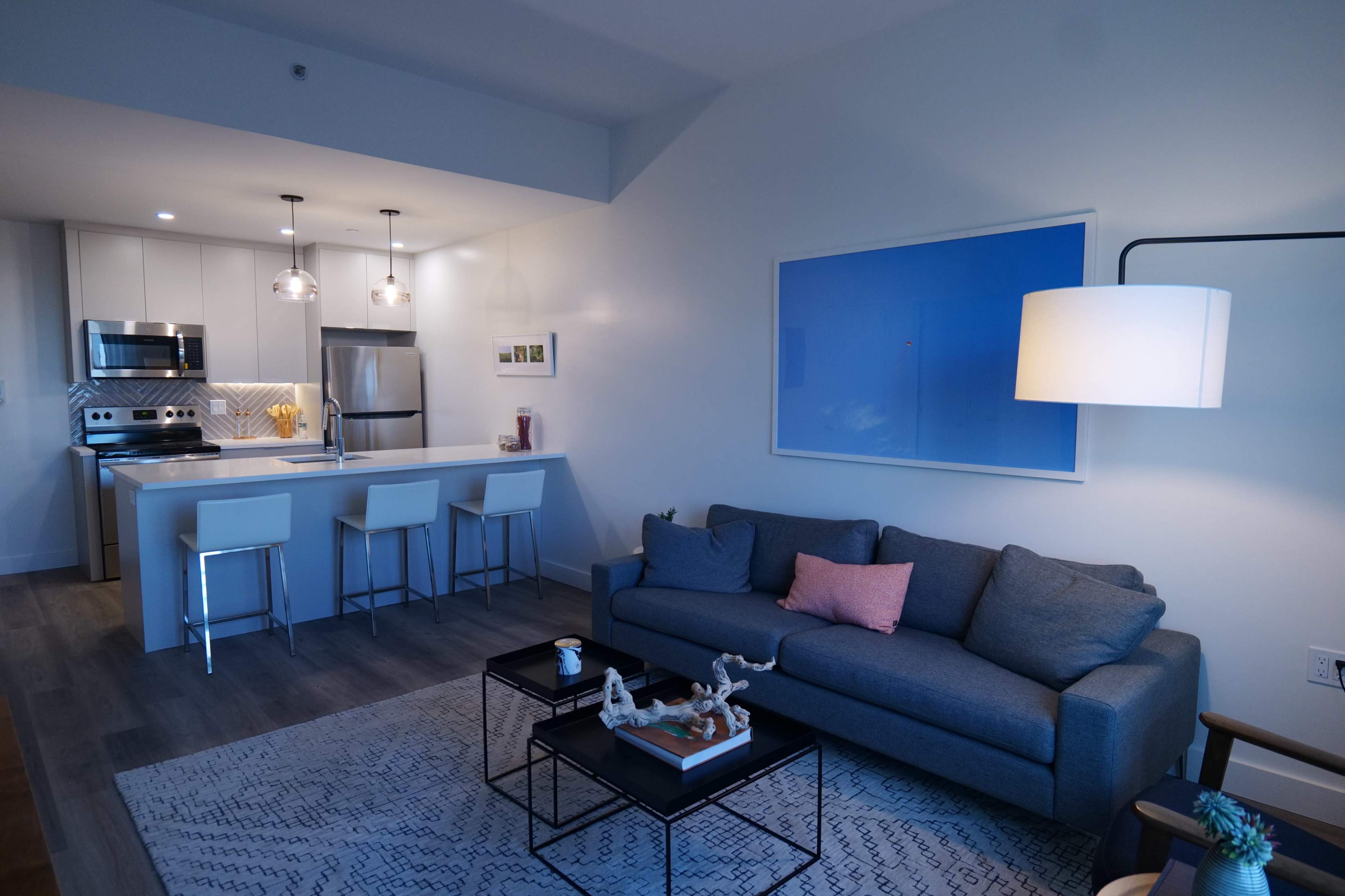A modern living room and kitchen area with a sofa, coffee table, and bar seating.