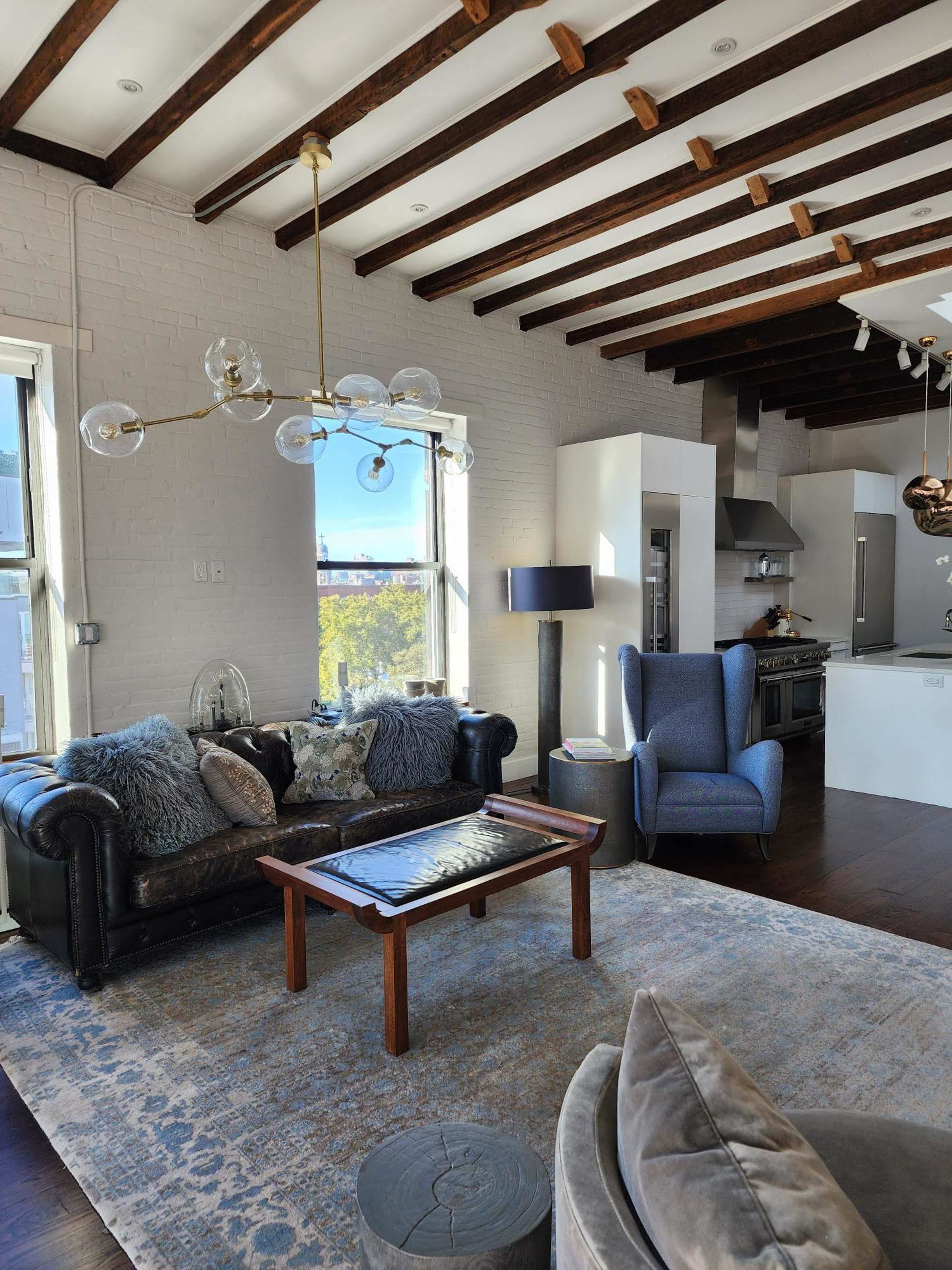 A stylish living room with a leather sofa, a coffee table, and modern furnishings beneath exposed beams.