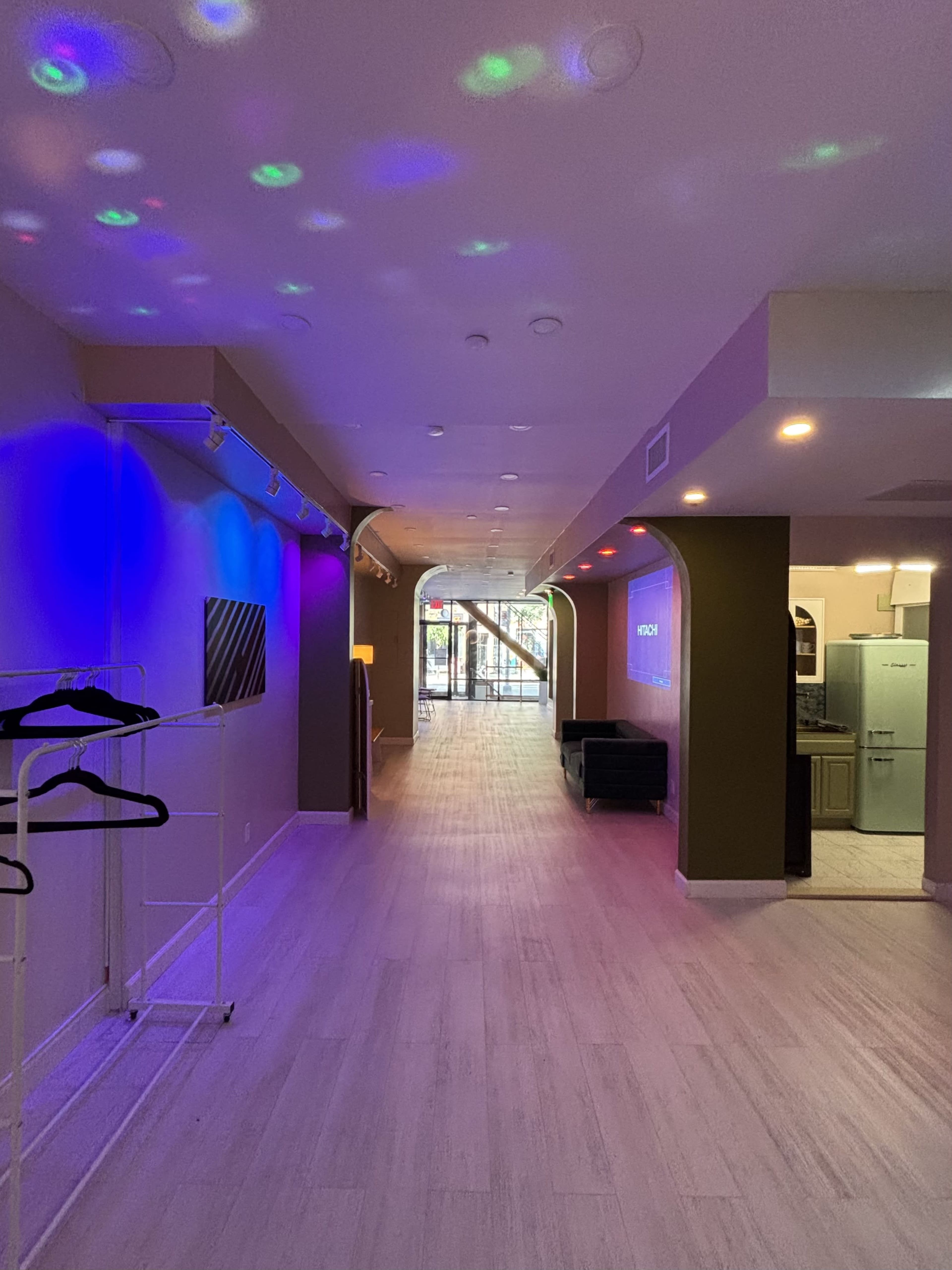 The image shows a brightly lit hallway with colorful lights projecting onto the walls, leading to a doorway at the end.