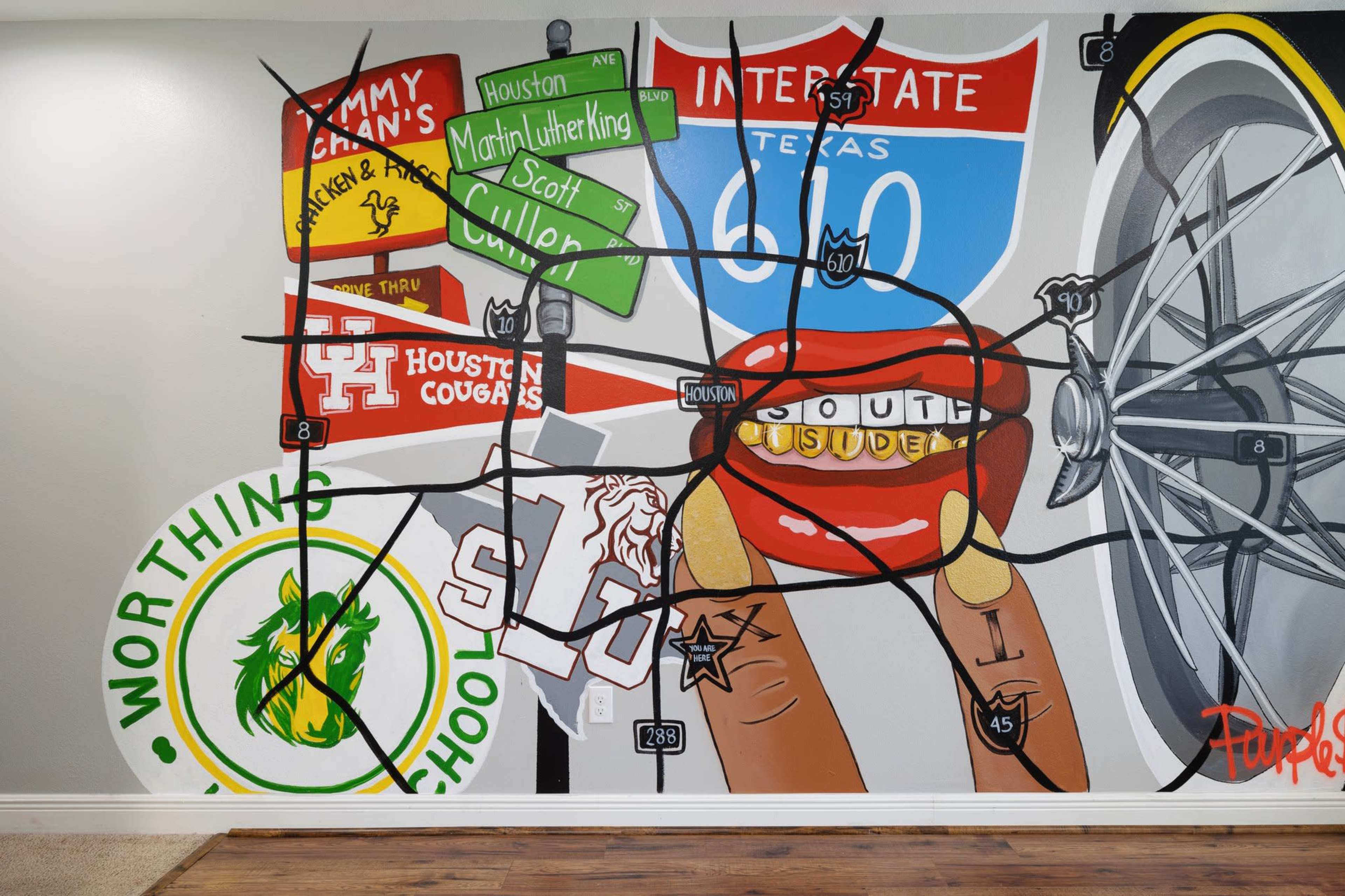 A large mural depicting various road signs and elements associated with Texas, including a bicycle wheel and symbols representing local schools and universities.