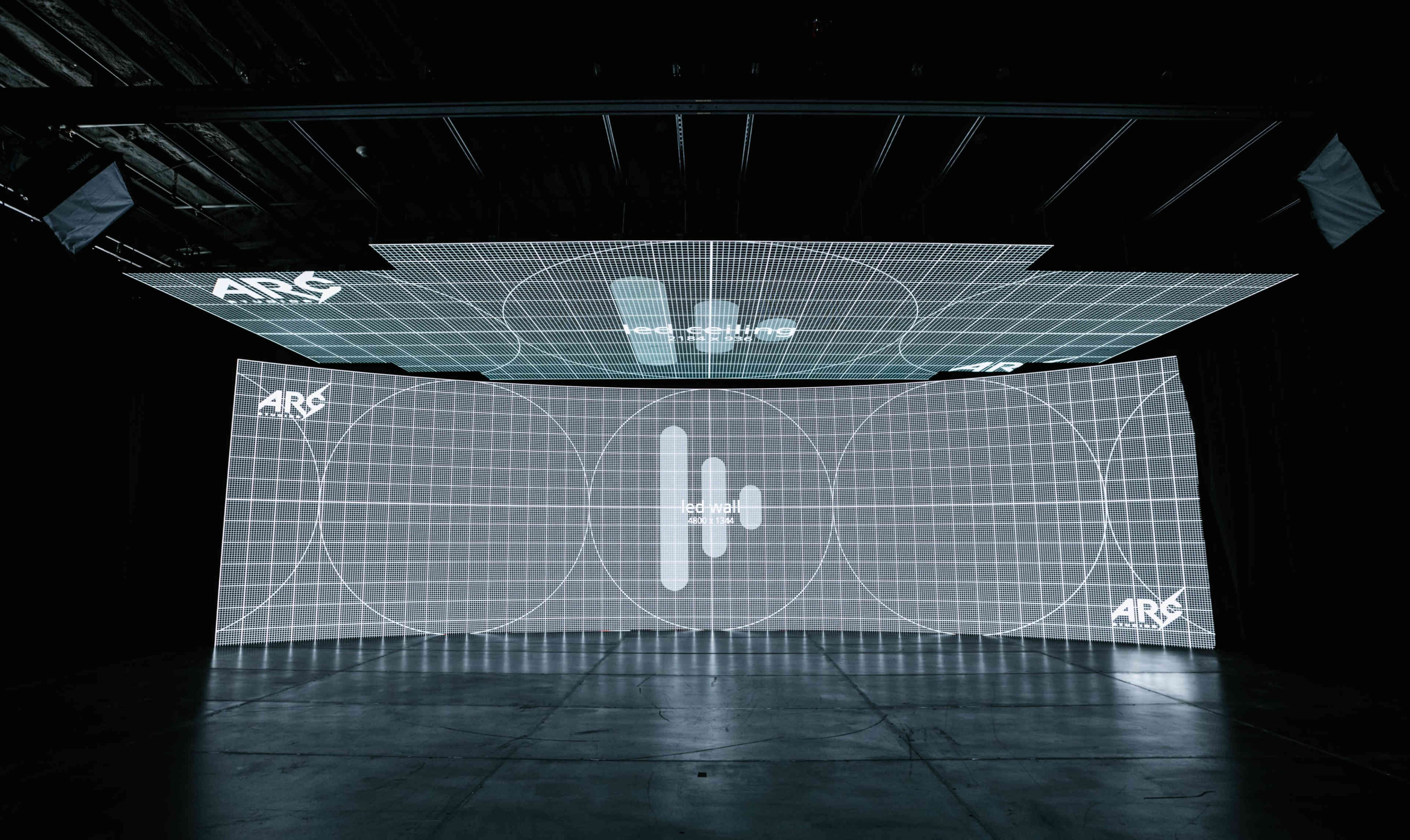 A large immersive installation features a grid pattern projected onto multiple surfaces in a darkened room.