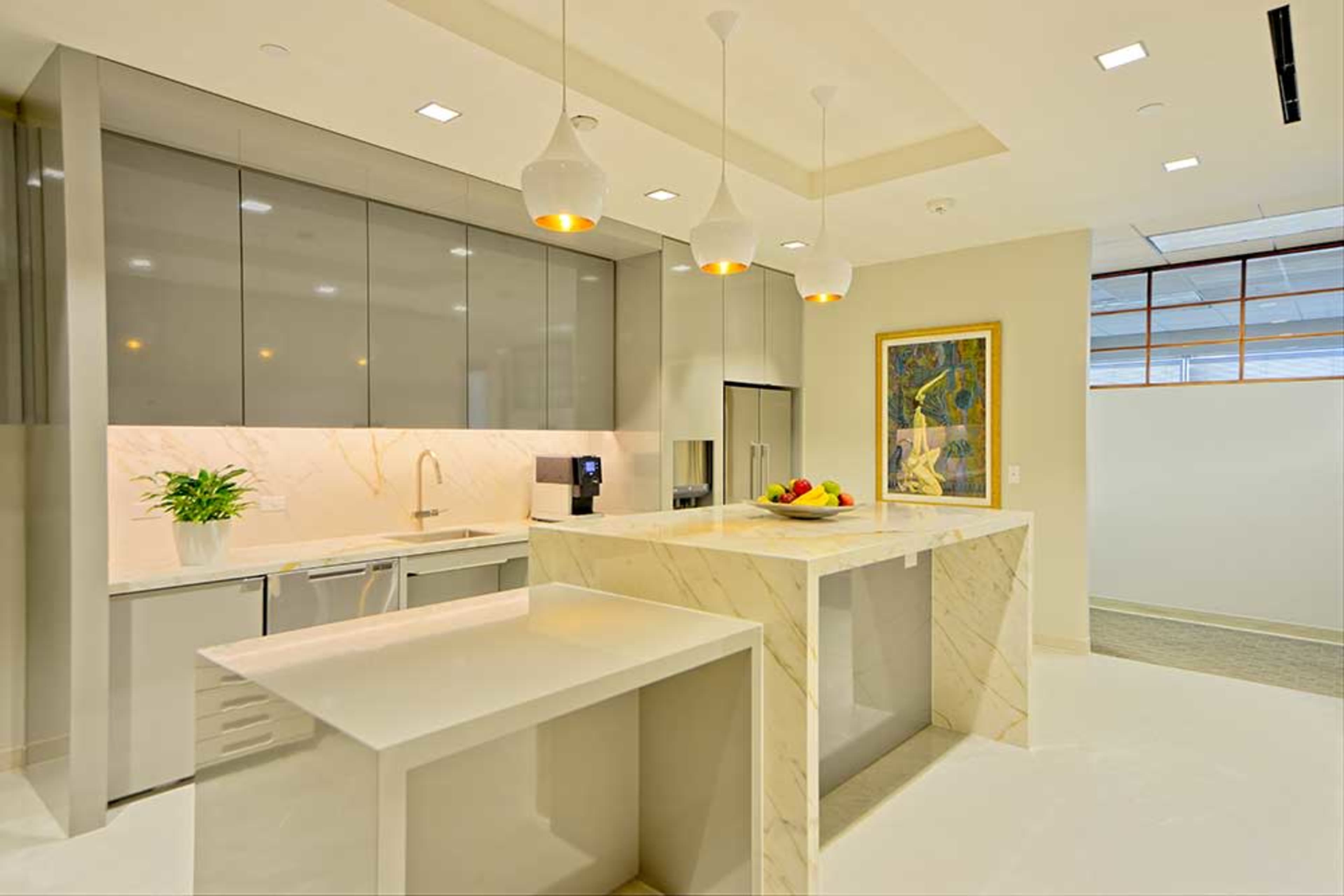 A modern kitchen with sleek gray cabinets, a marble island, and pendant lighting above the countertop.