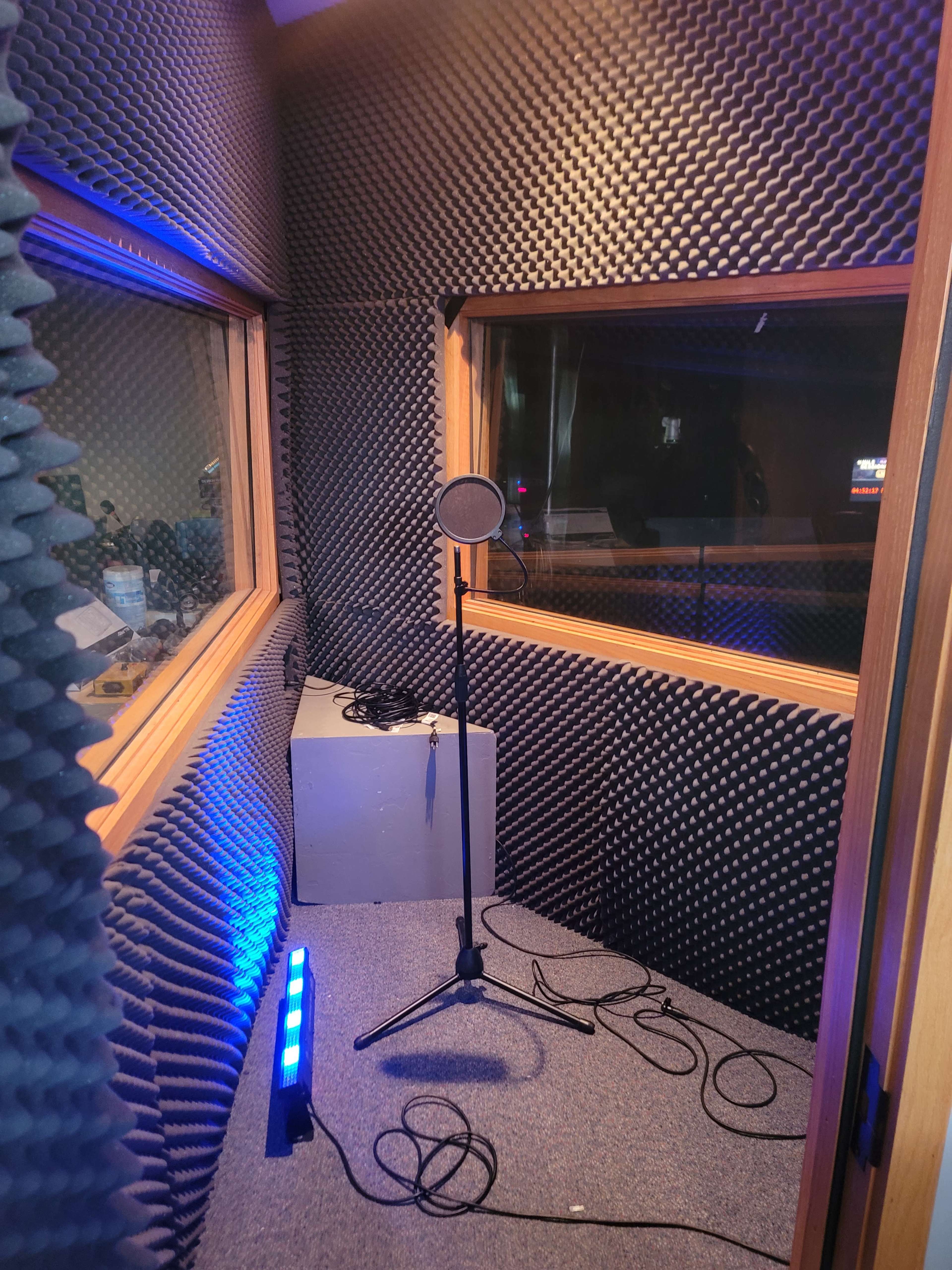 A soundproof recording booth with walls covered in acoustic foam and a microphone on a stand.