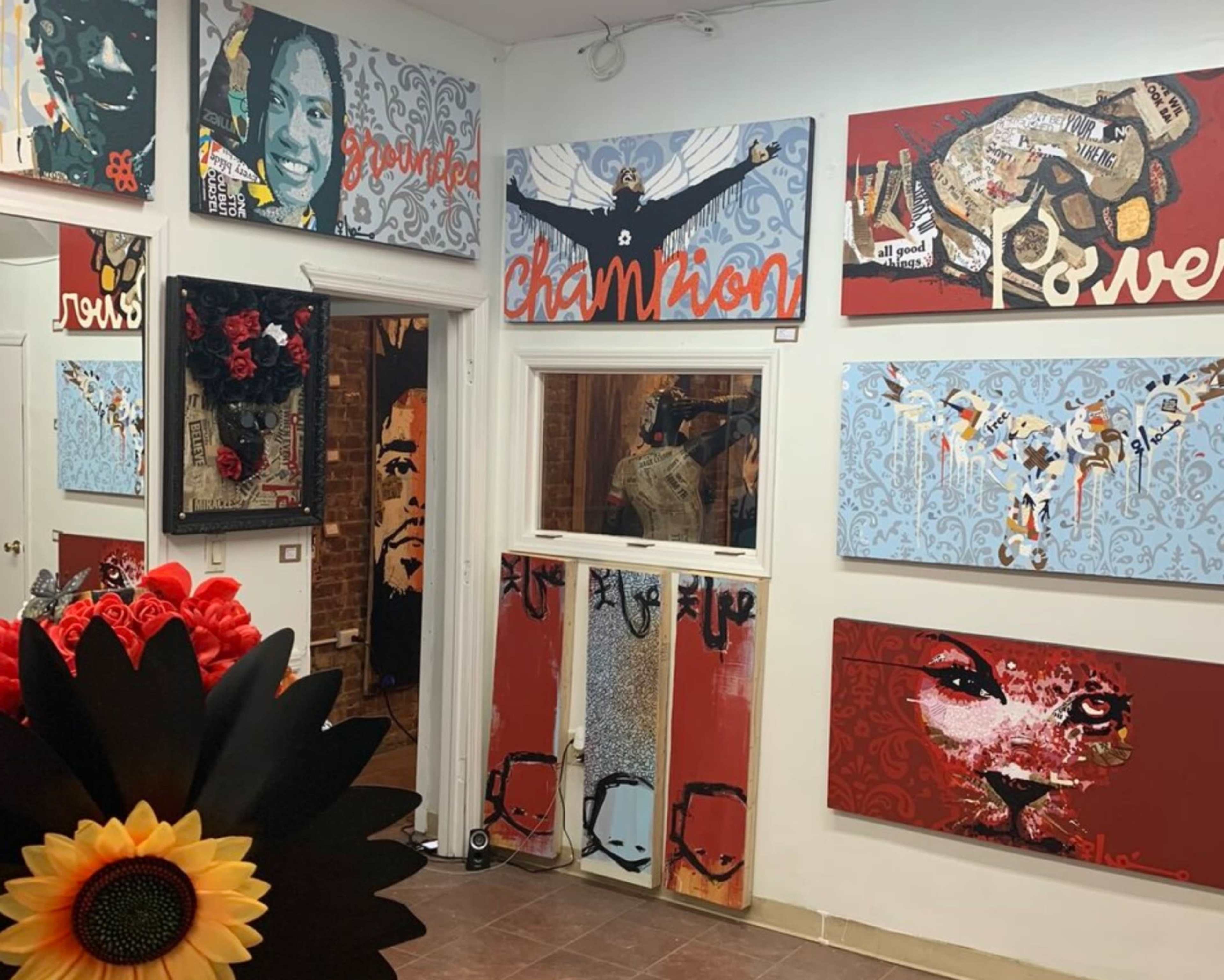 An art gallery interior with various colorful paintings displayed on the walls, featuring portraits and abstract designs.