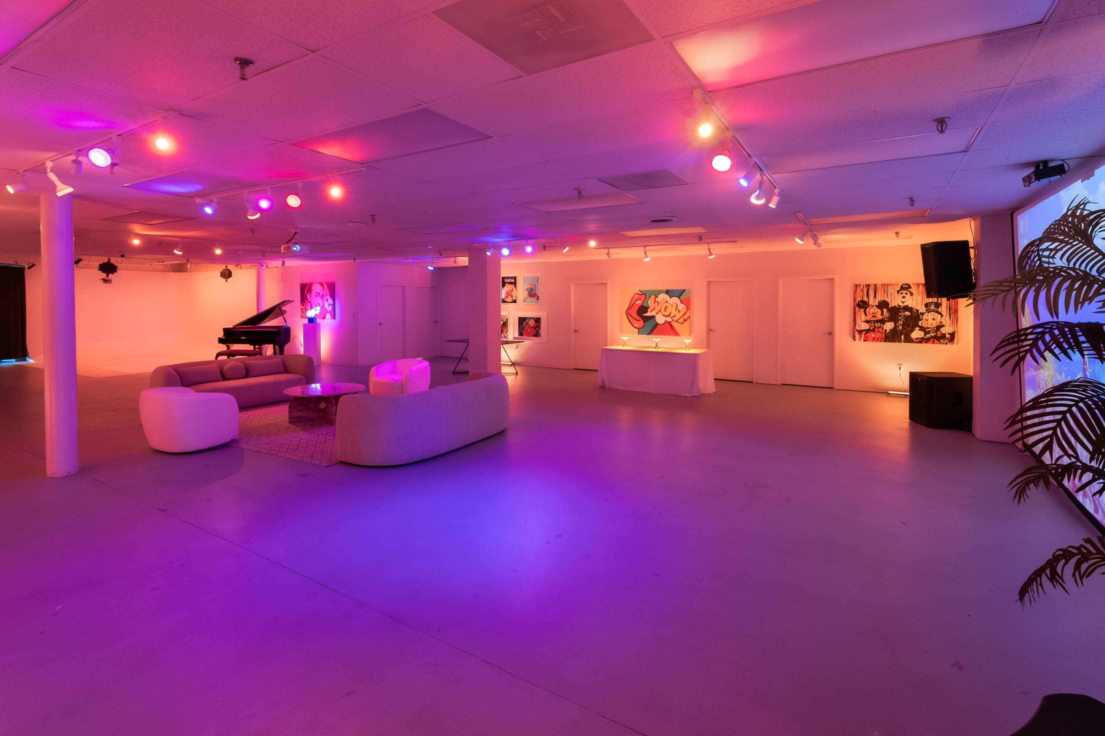 The image shows a spacious room with purple and pink lighting, featuring a piano, a couch, and several art pieces on the walls.