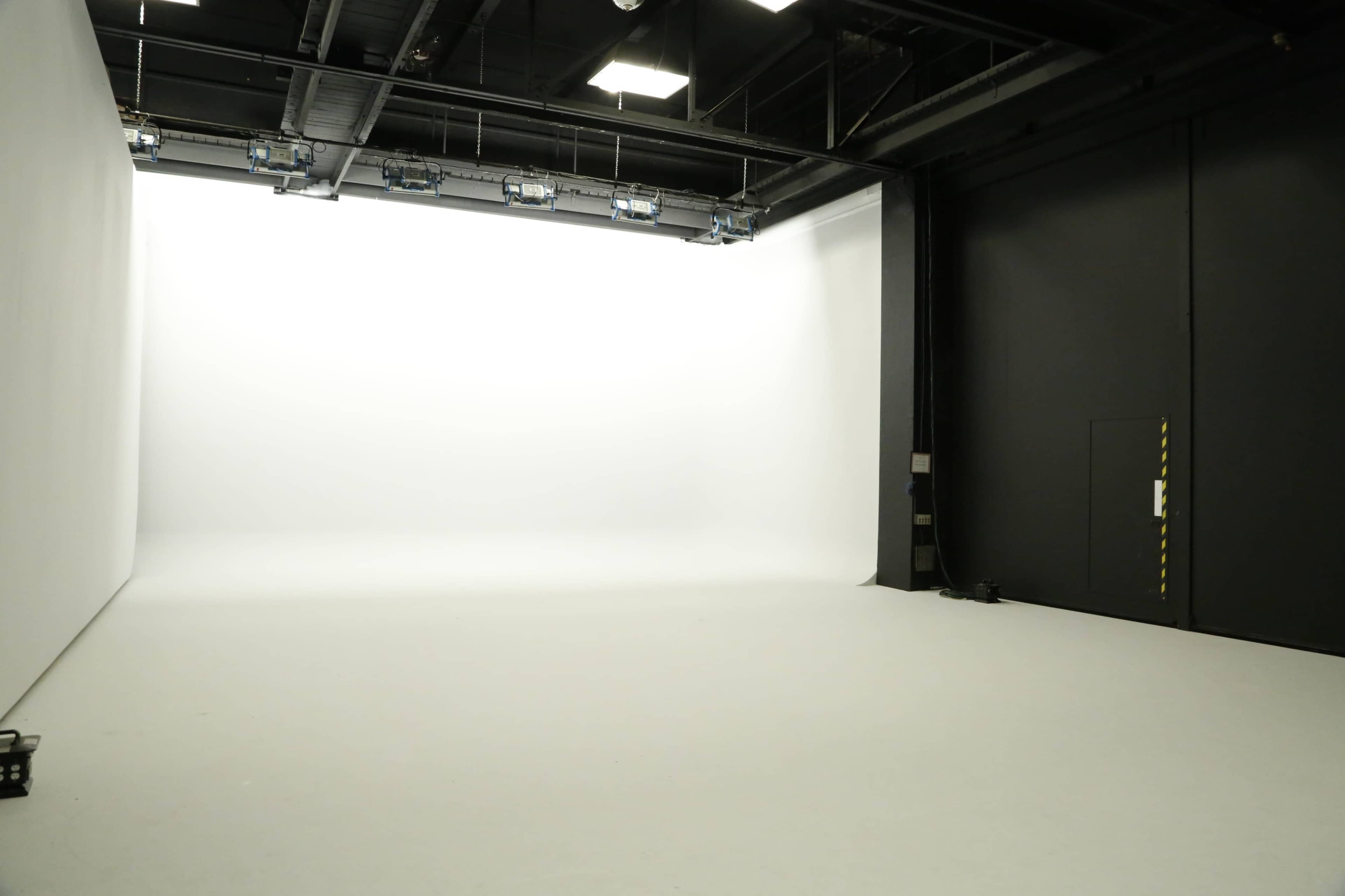 A spacious photography studio with a large white backdrop and a smooth floor.
