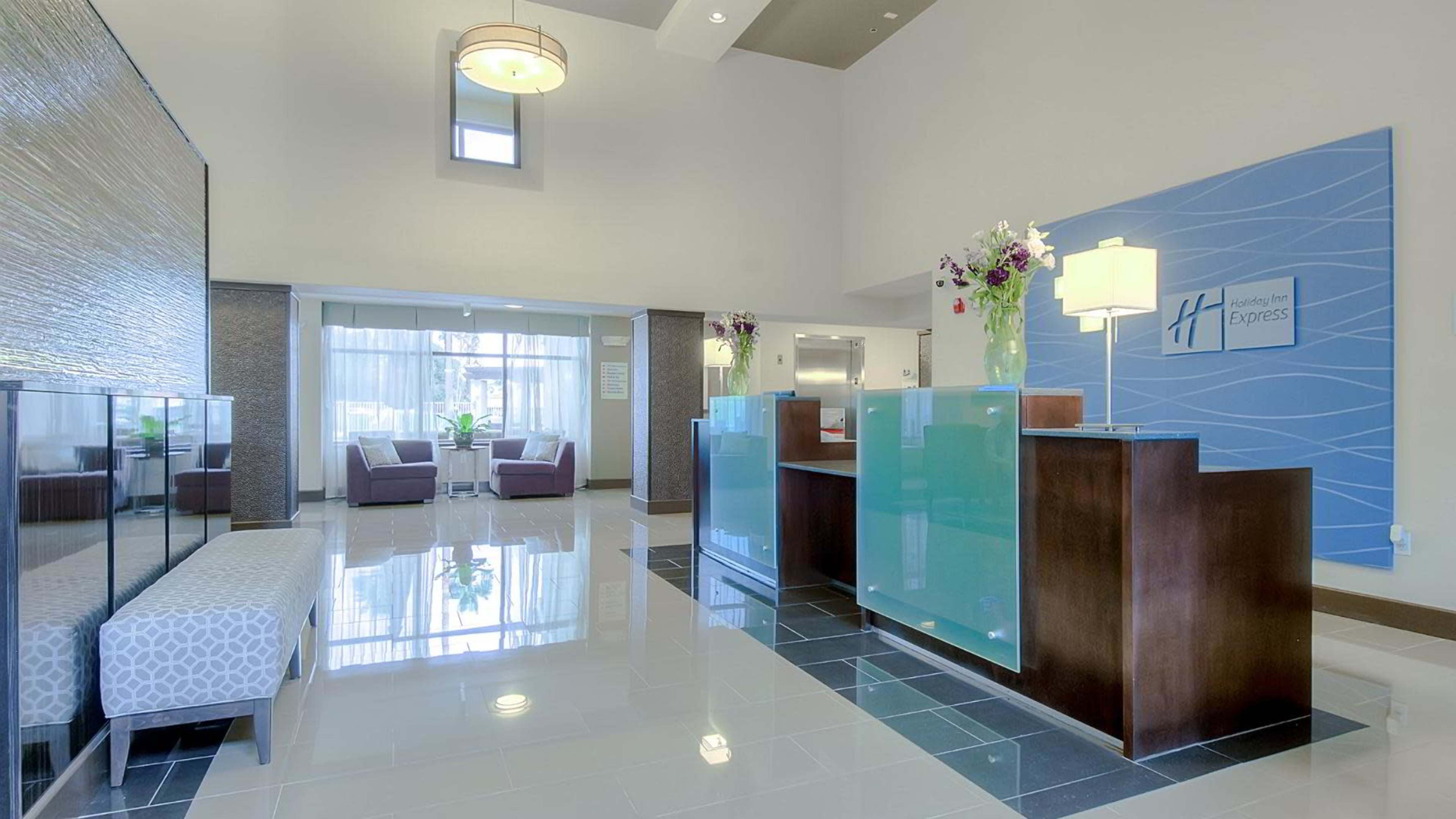 The image shows the interior of a hotel lobby with a reception desk, seating area, and decorative elements.