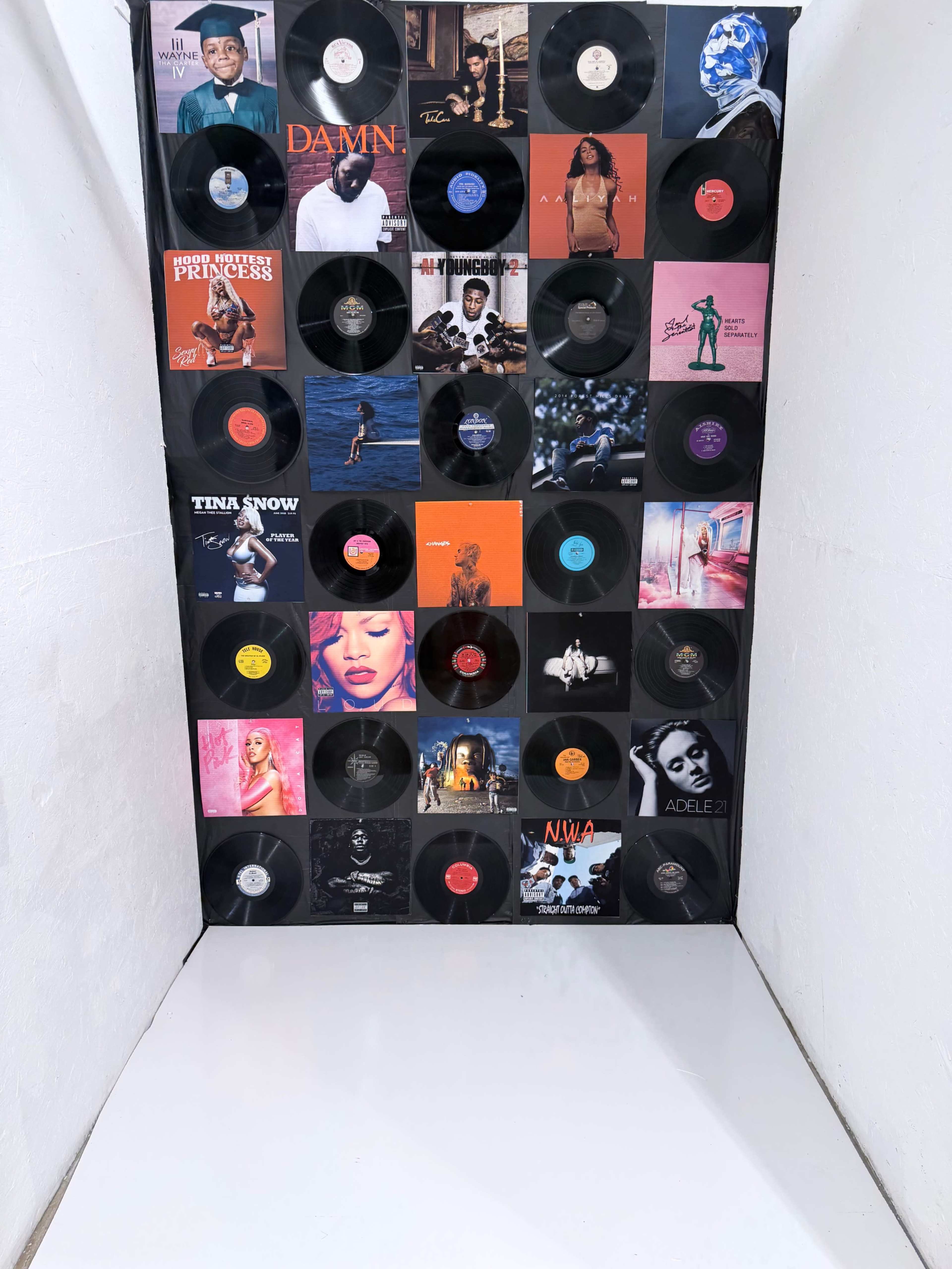 The image features a wall covered with arranged vinyl record covers in a grid pattern.