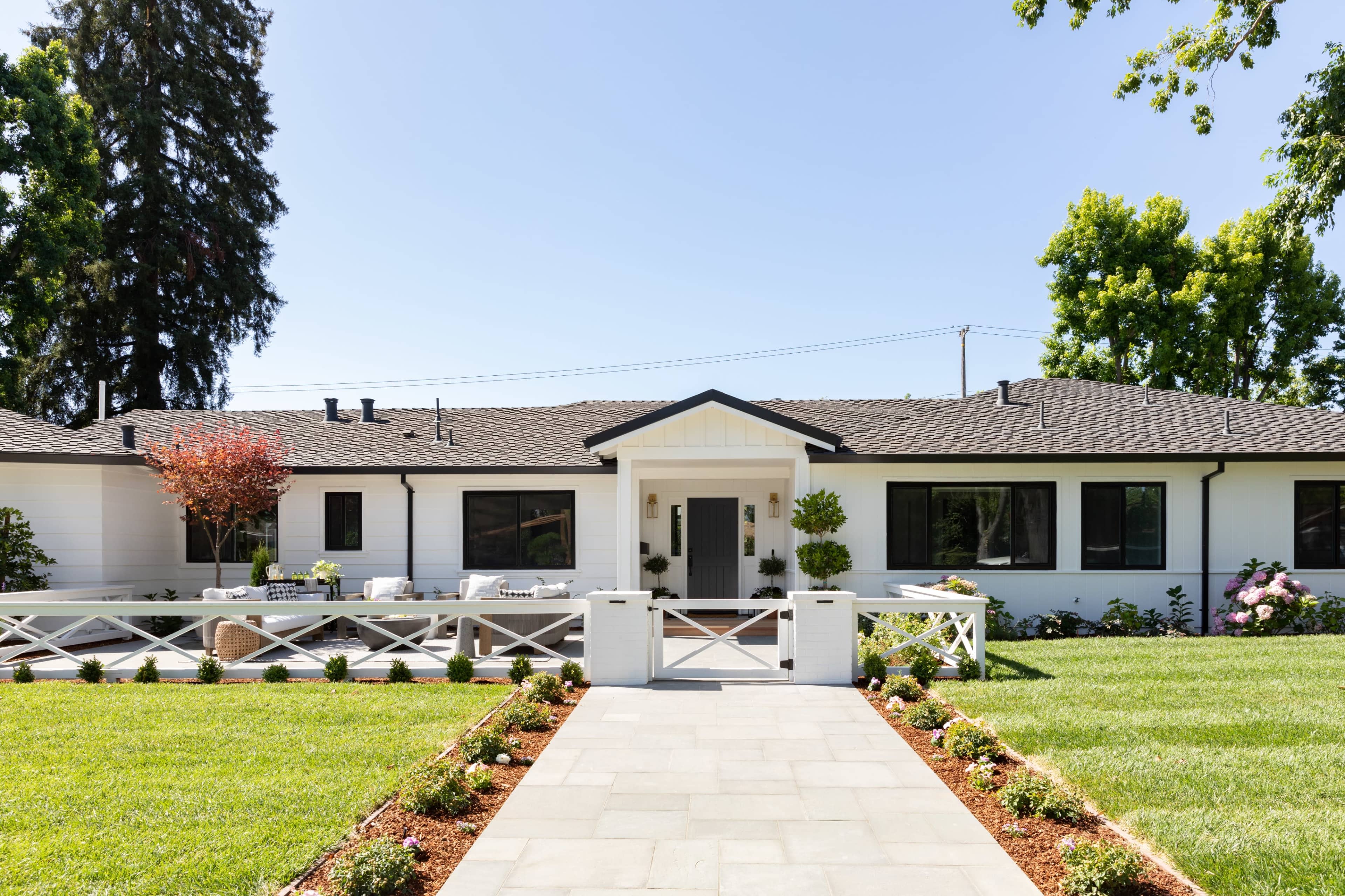 A modern, single-story house with a white facade and a landscaped front yard featuring a stone walkway.