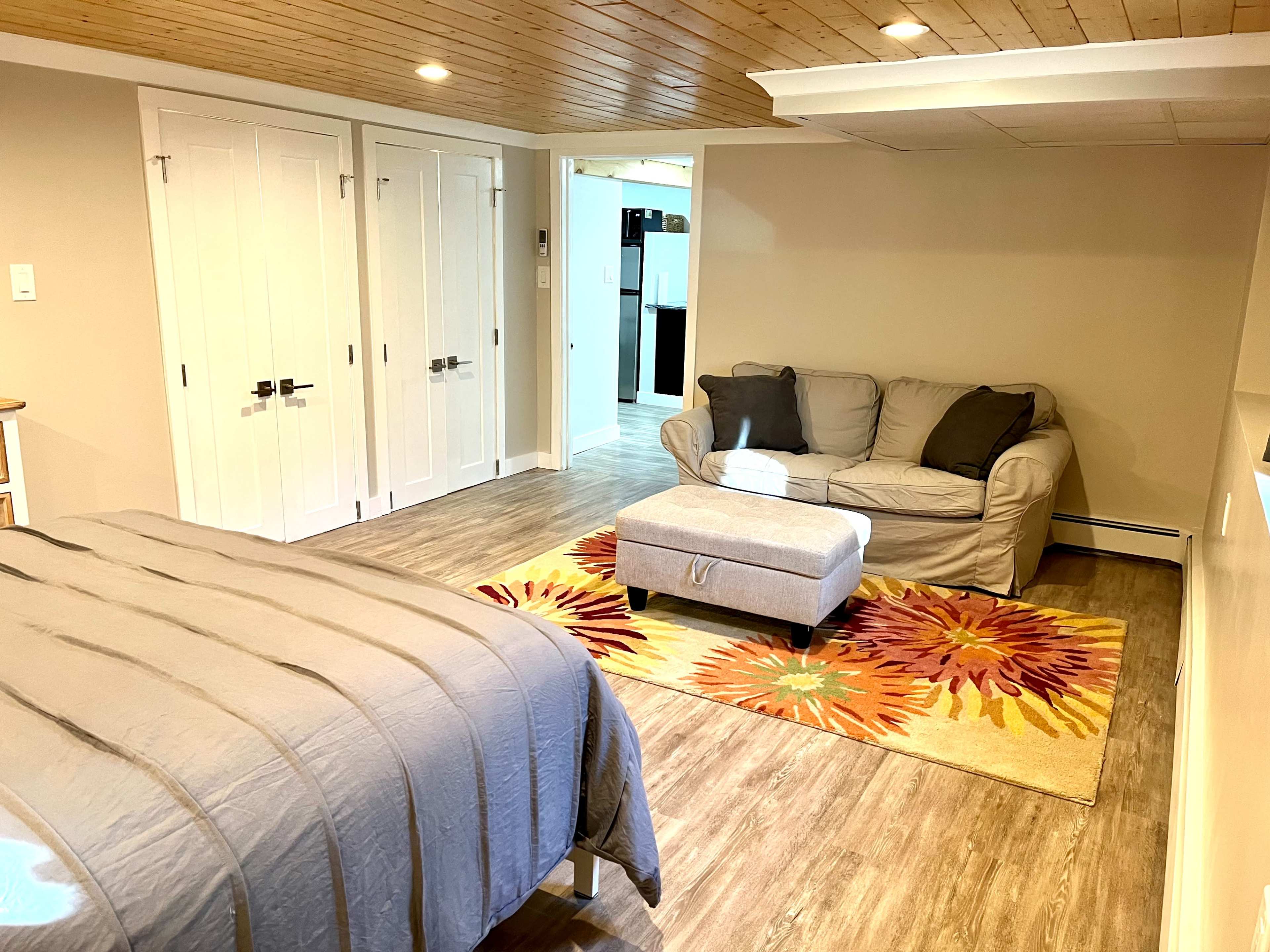 A spacious bedroom featuring a bed, a couch, and a colorful area rug with floral patterns.