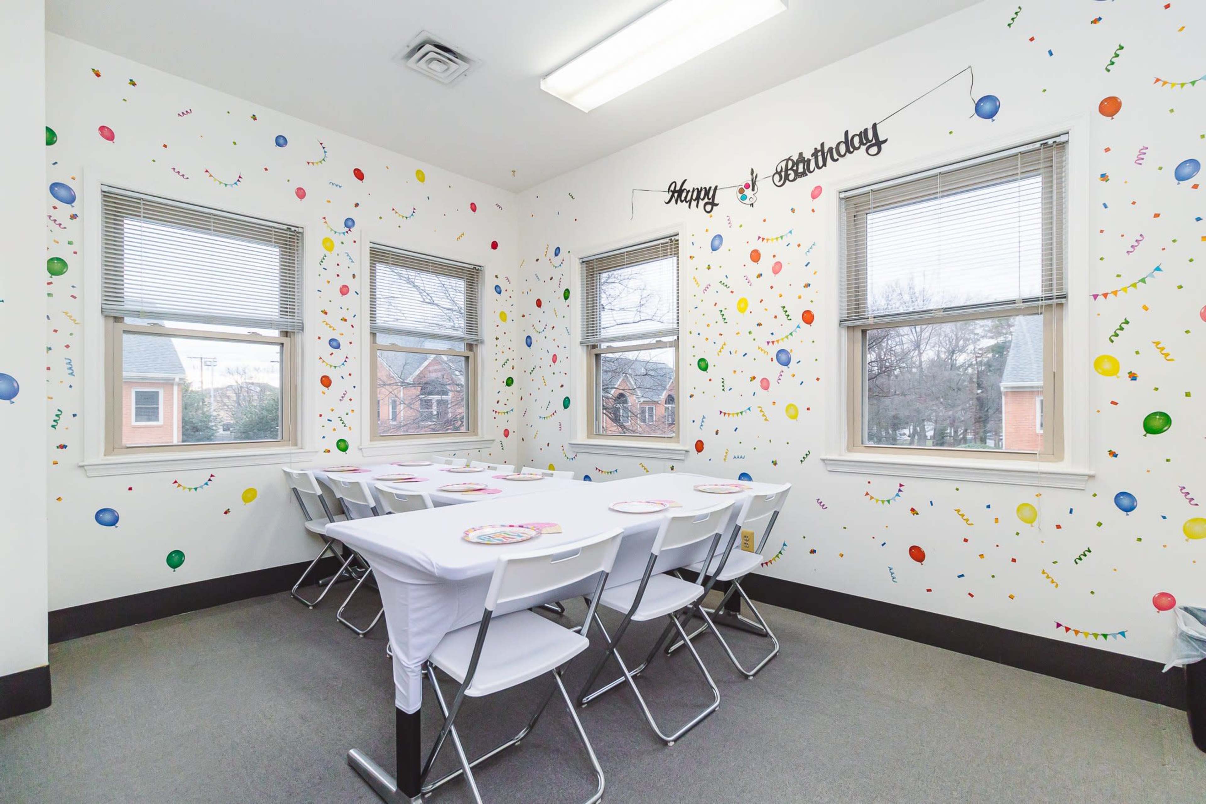 A birthday celebration room with a table set for guests, surrounded by colorful decorations on the walls.