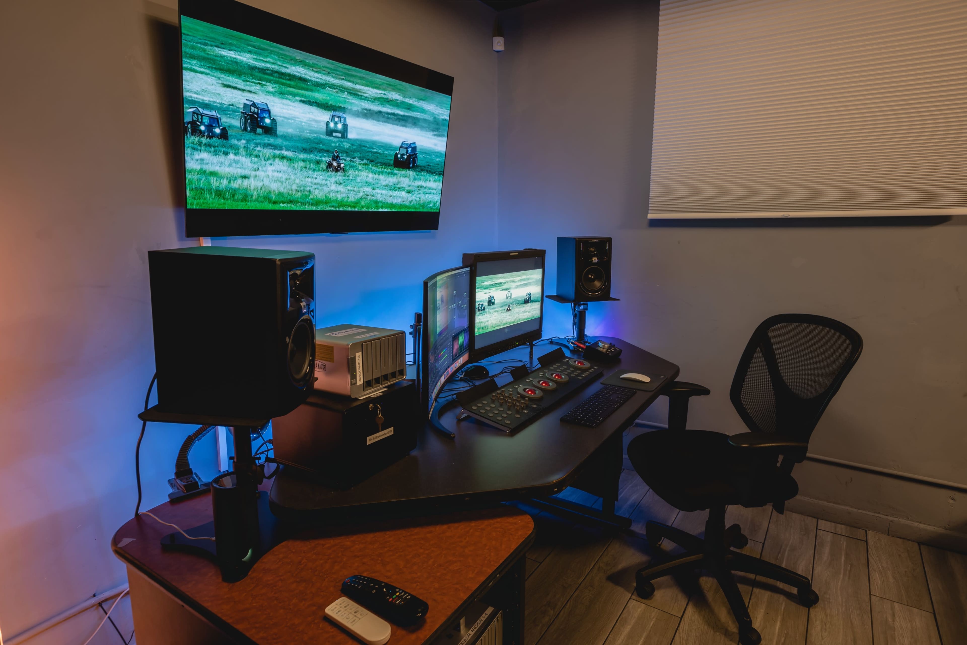 A recording studio setup featuring multiple monitors, speakers, and a control panel in a well-lit room.
